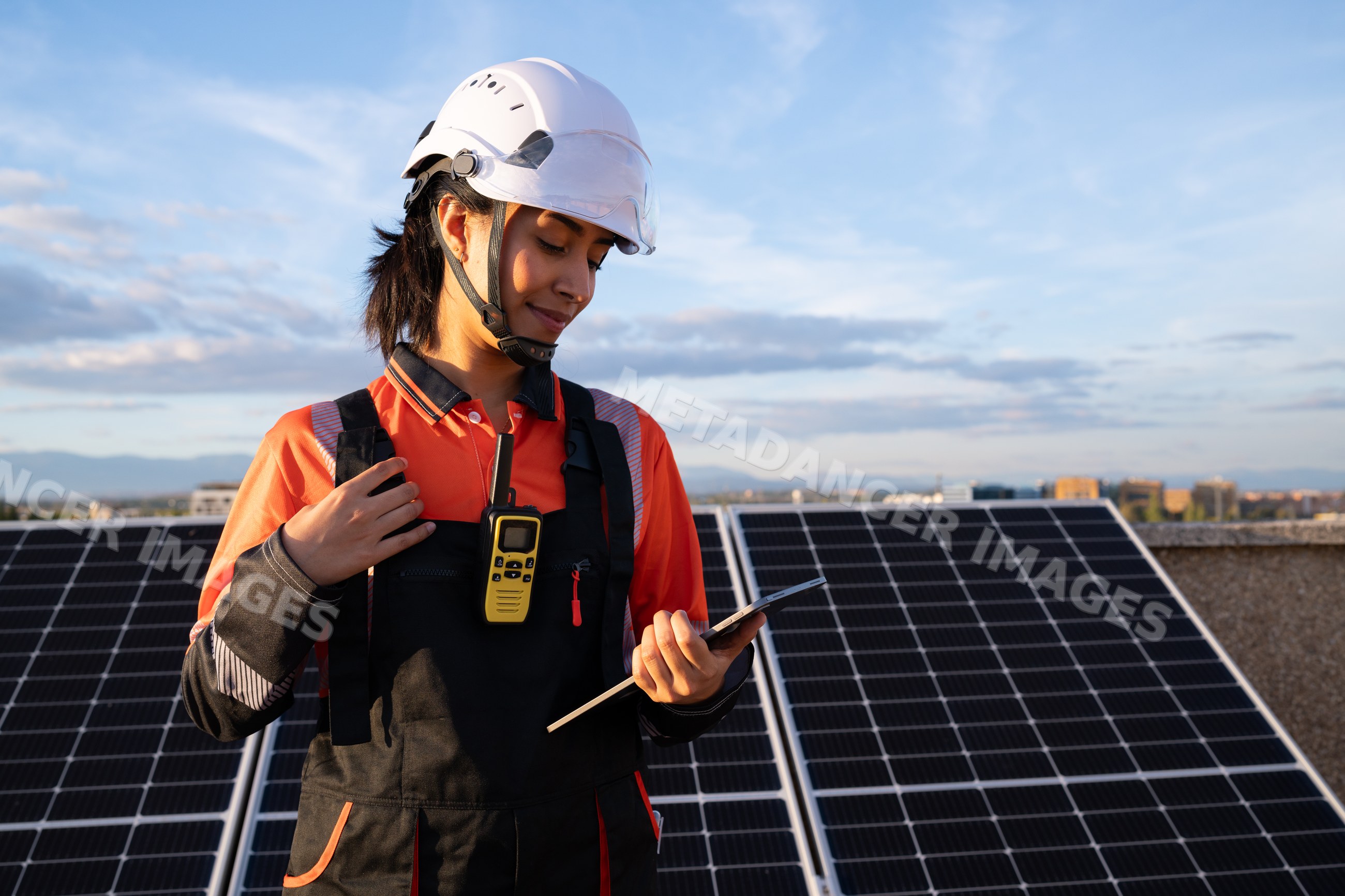 Hispanic woman solar panel technician inspecting solar panels outdoors