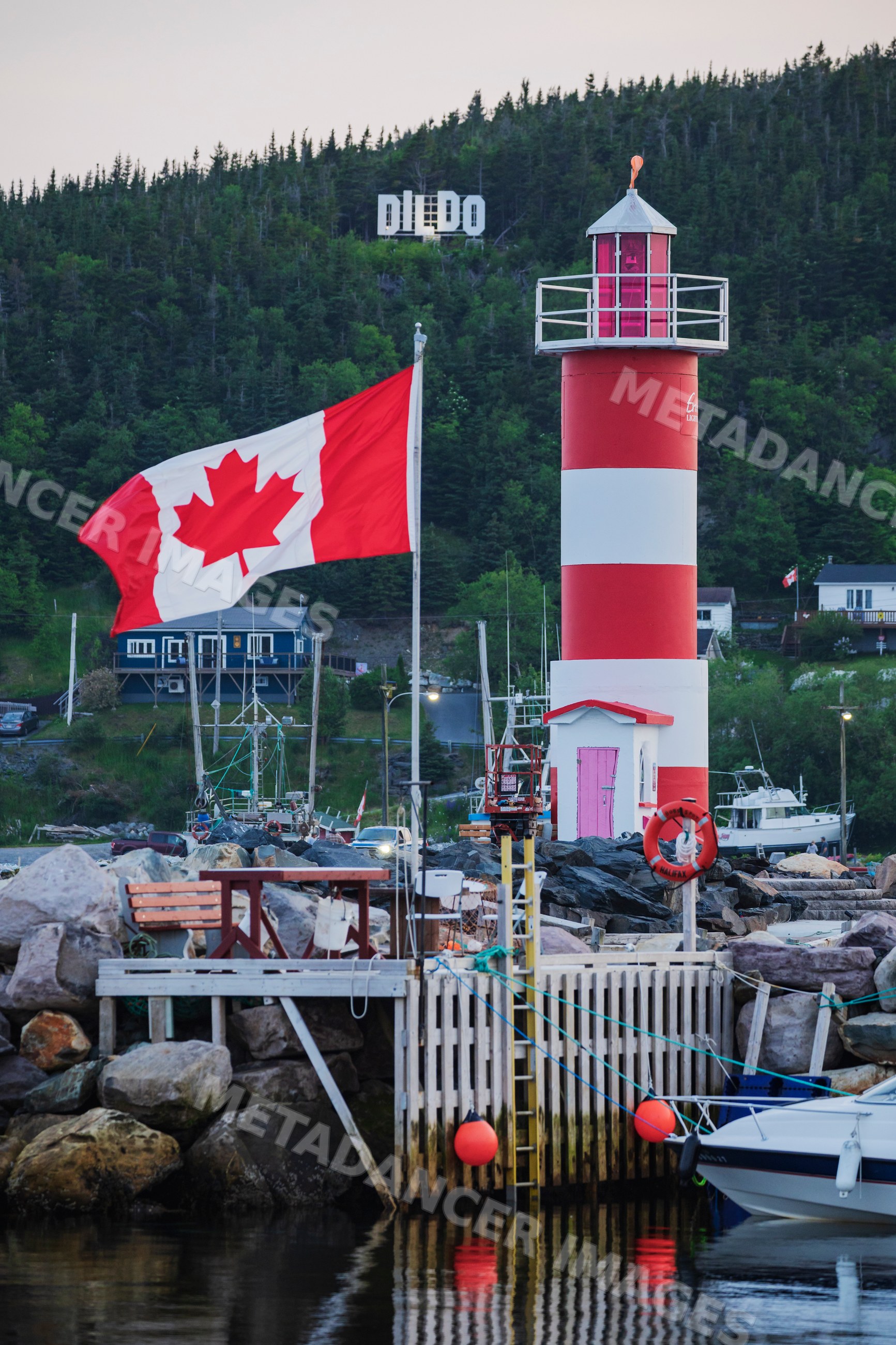 Lighthouse and canadian flag at harbor dock with Dildo Sign