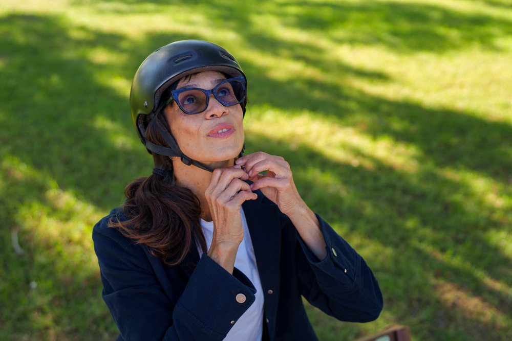 Hispanic woman adjusting helmet strap outdoors in park