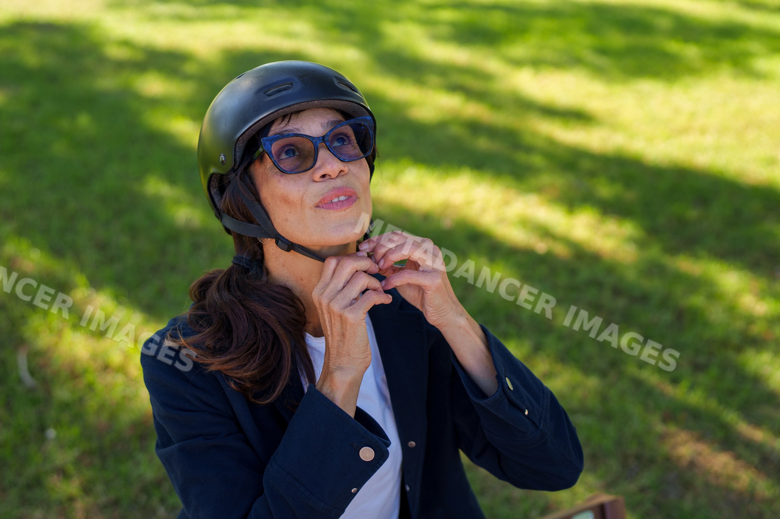 Hispanic woman adjusting helmet strap outdoors in park