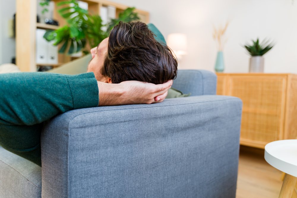 White man relaxing on couch in contemporary living room