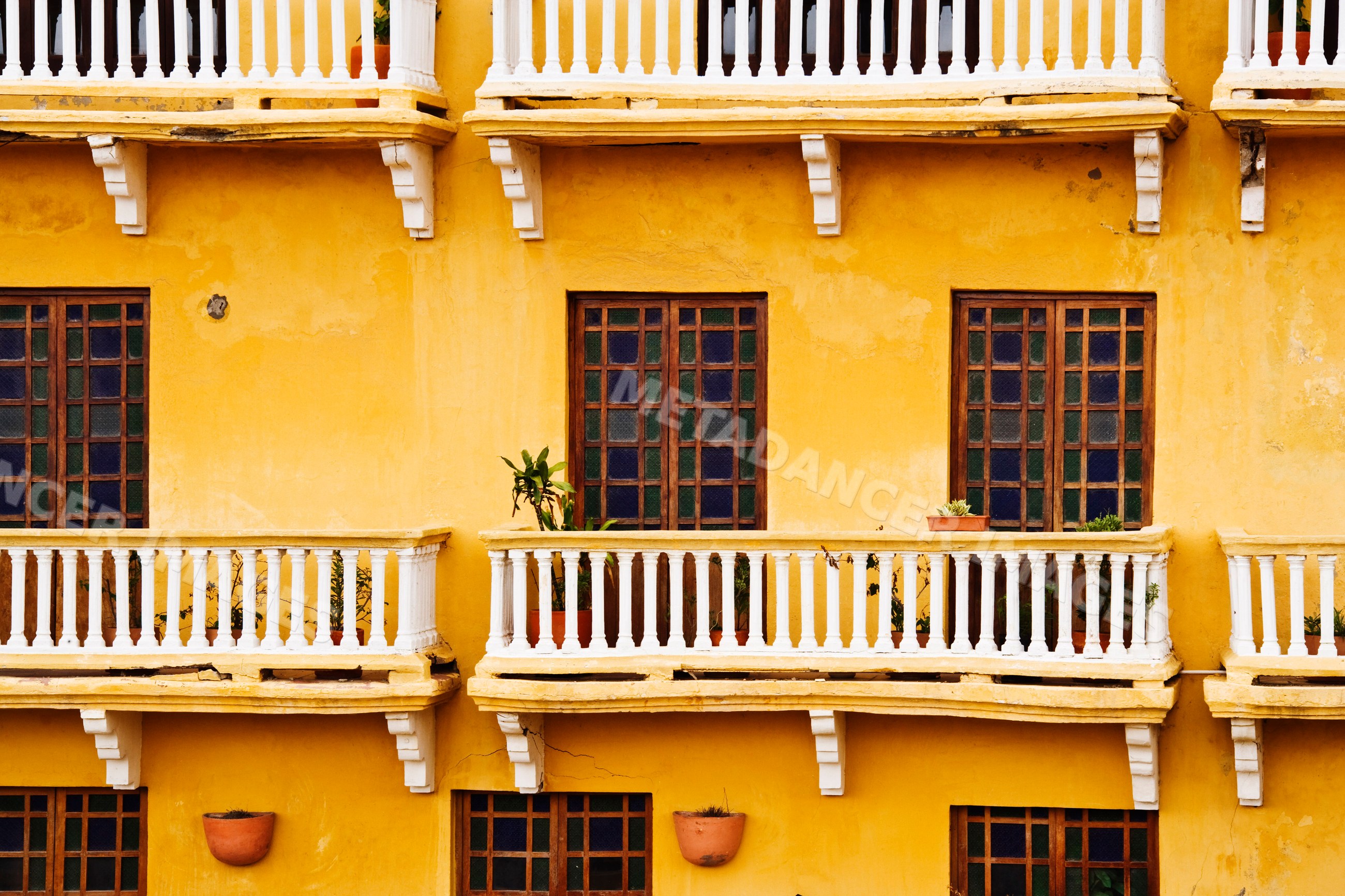 Yellow colonial building facade with balconies and wooden windows