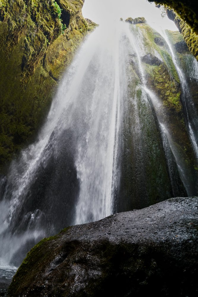 A moss-covered rocky waterfall flows in a natural Iceland landscape