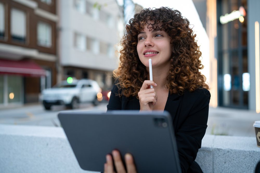 Young white woman holding tablet and stylus in urban Madrid setting