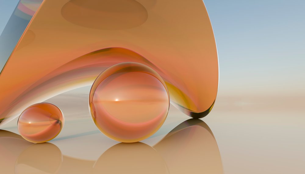 Two orange glass spheres next to a curved glass shape on a reflective