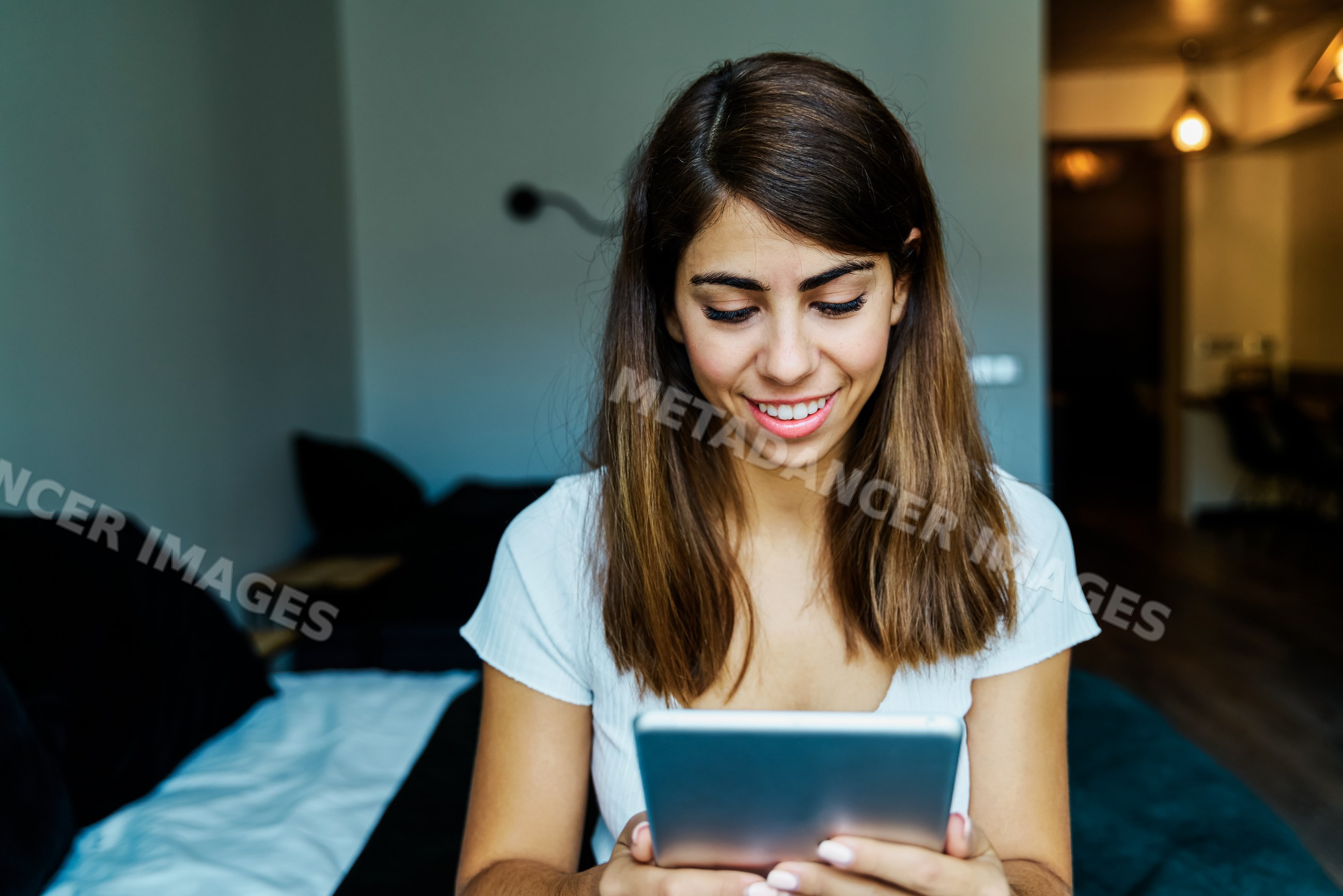 A young woman happily using a tablet indoors