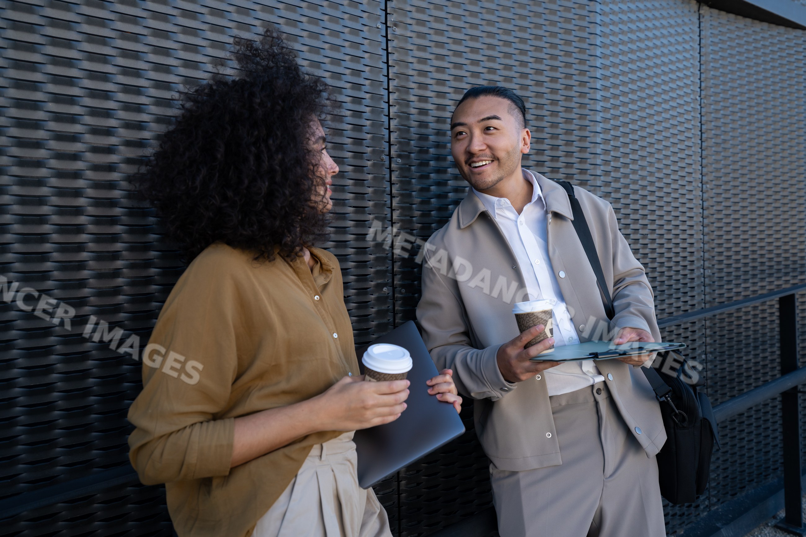 Two people conversing outdoors with coffee and work items in Madrid