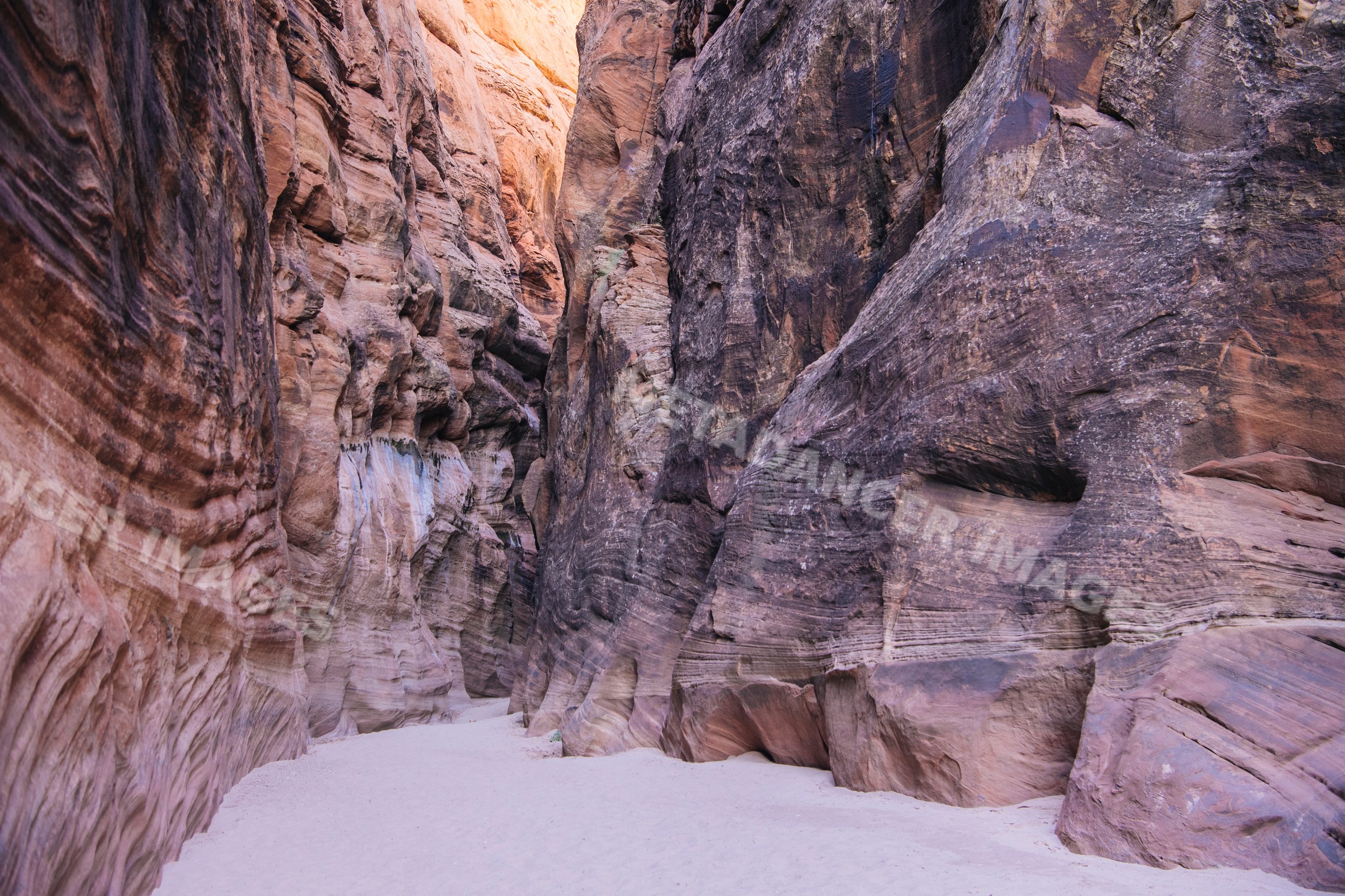Buckskin gulch slot canyon with sandy floor and towering rock walls