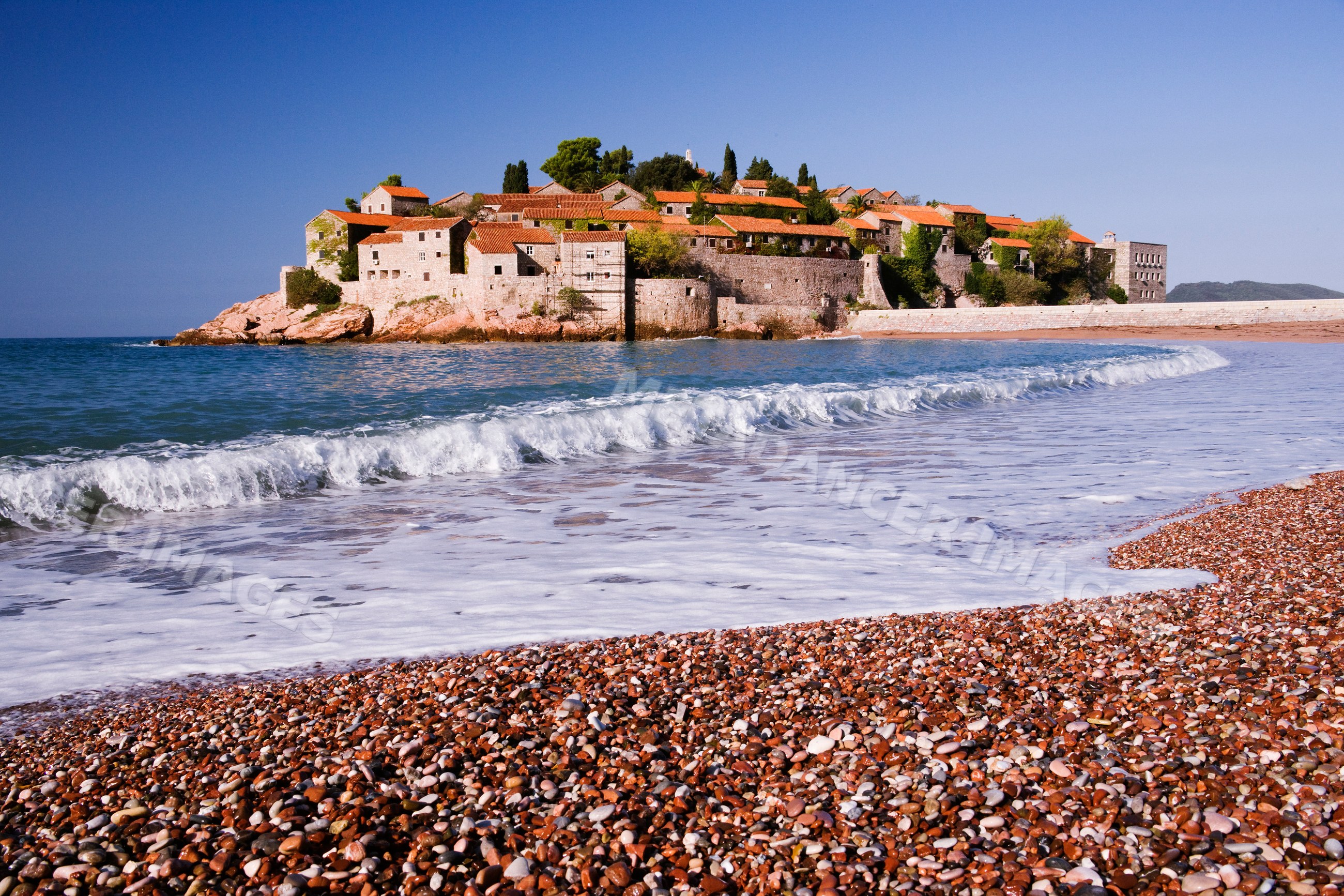 Sveti stefan island village with pebble beach and waves