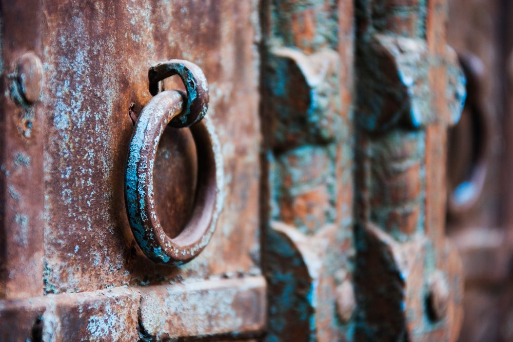 Rusty metal ring door handle on old weathered door
