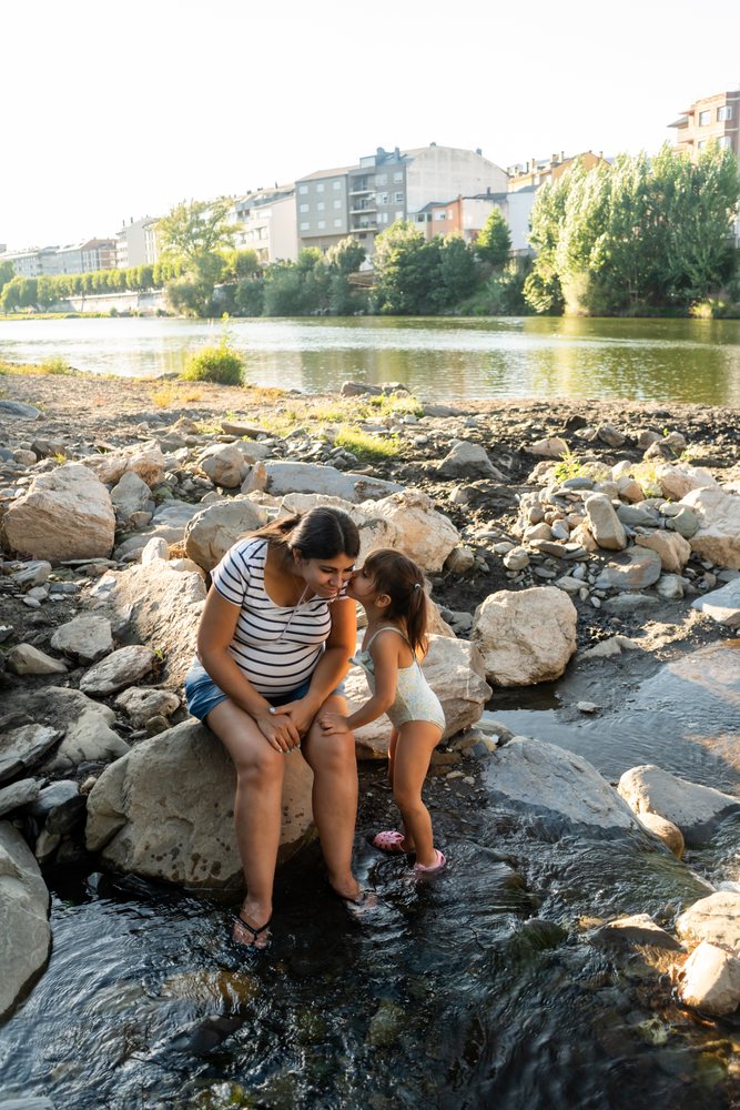 Pregnant white woman enjoys a loving moment with her child by a river