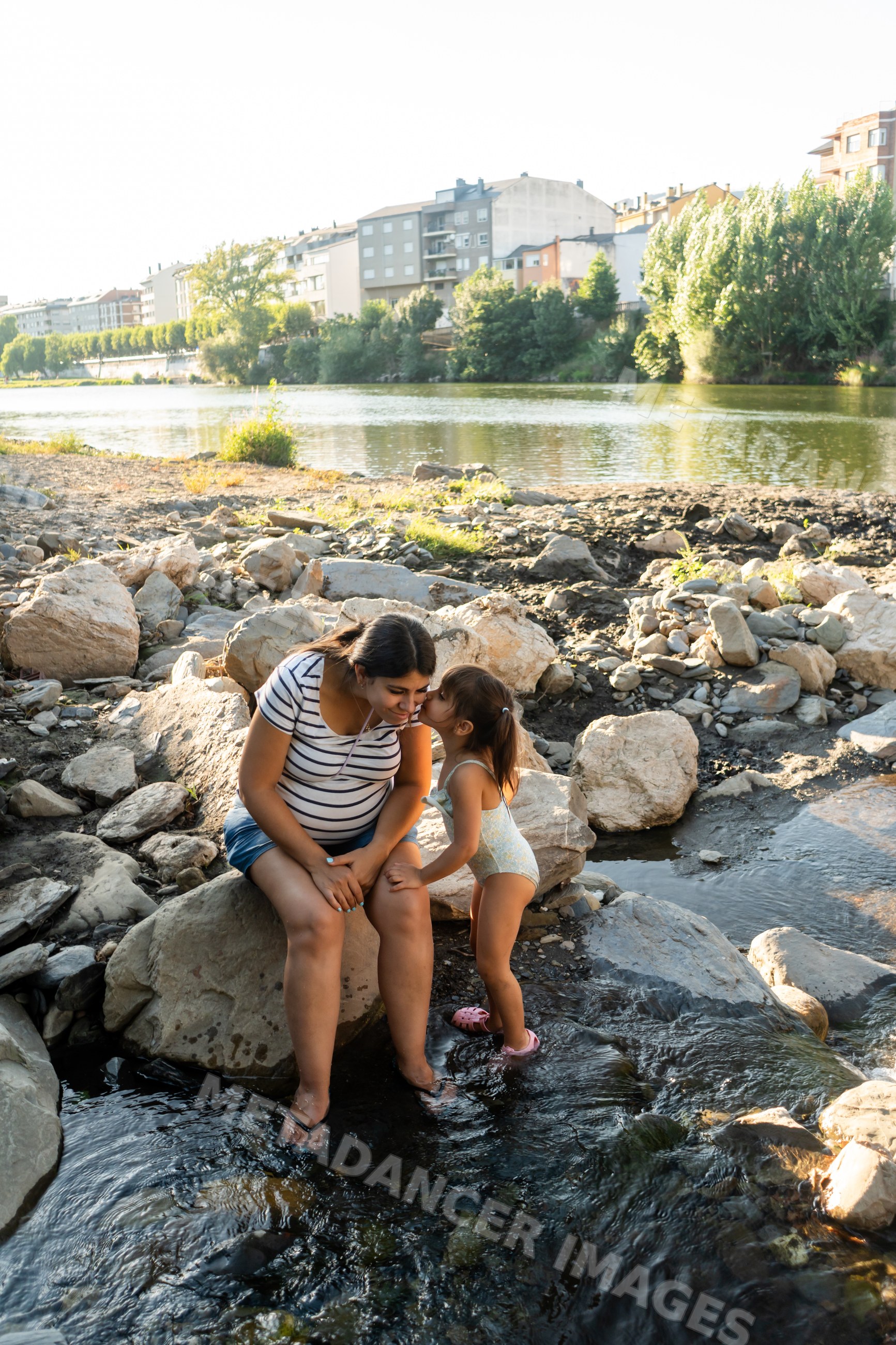 Pregnant white woman enjoys a loving moment with her child by a river