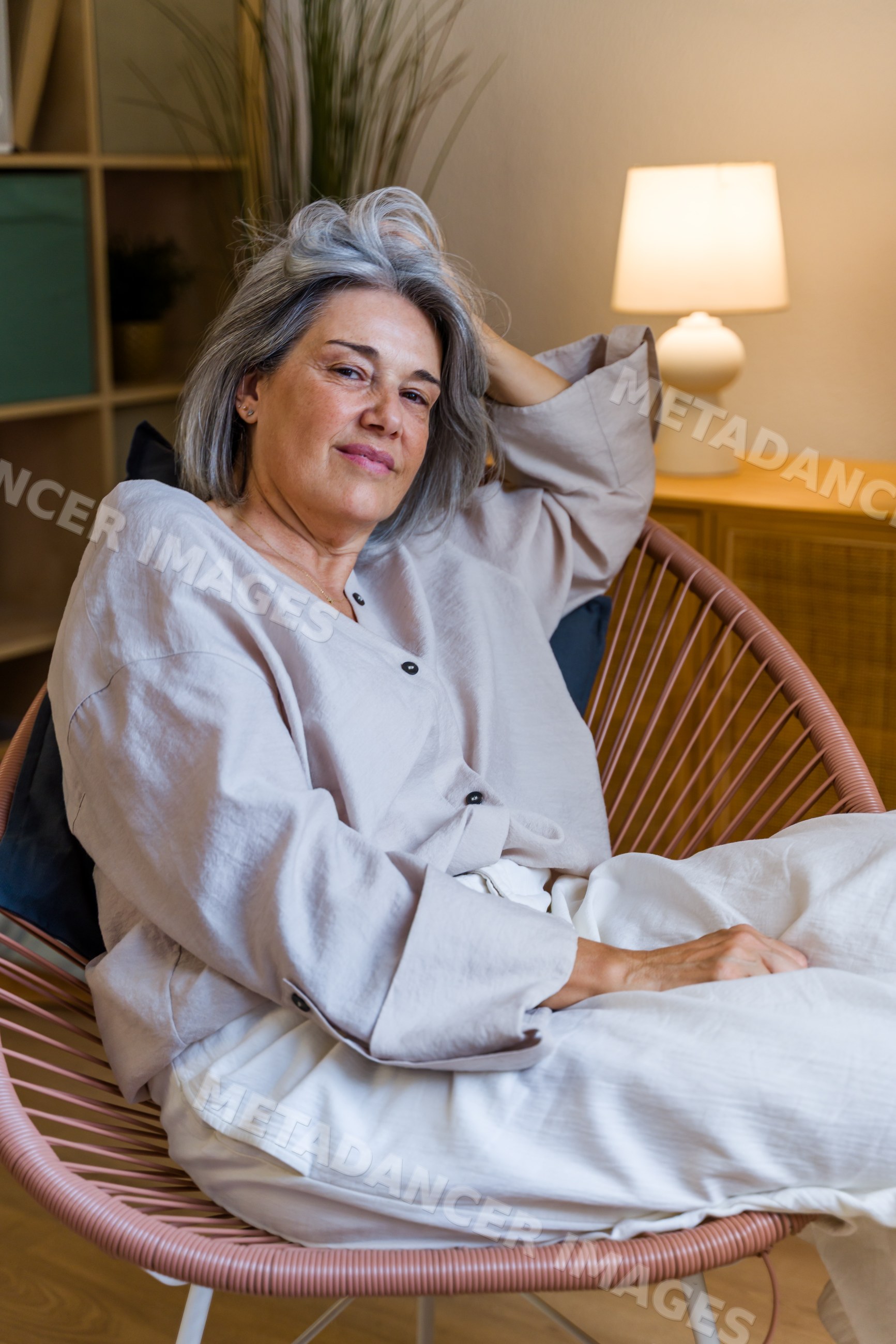 White woman relaxing in modern chair at home interior