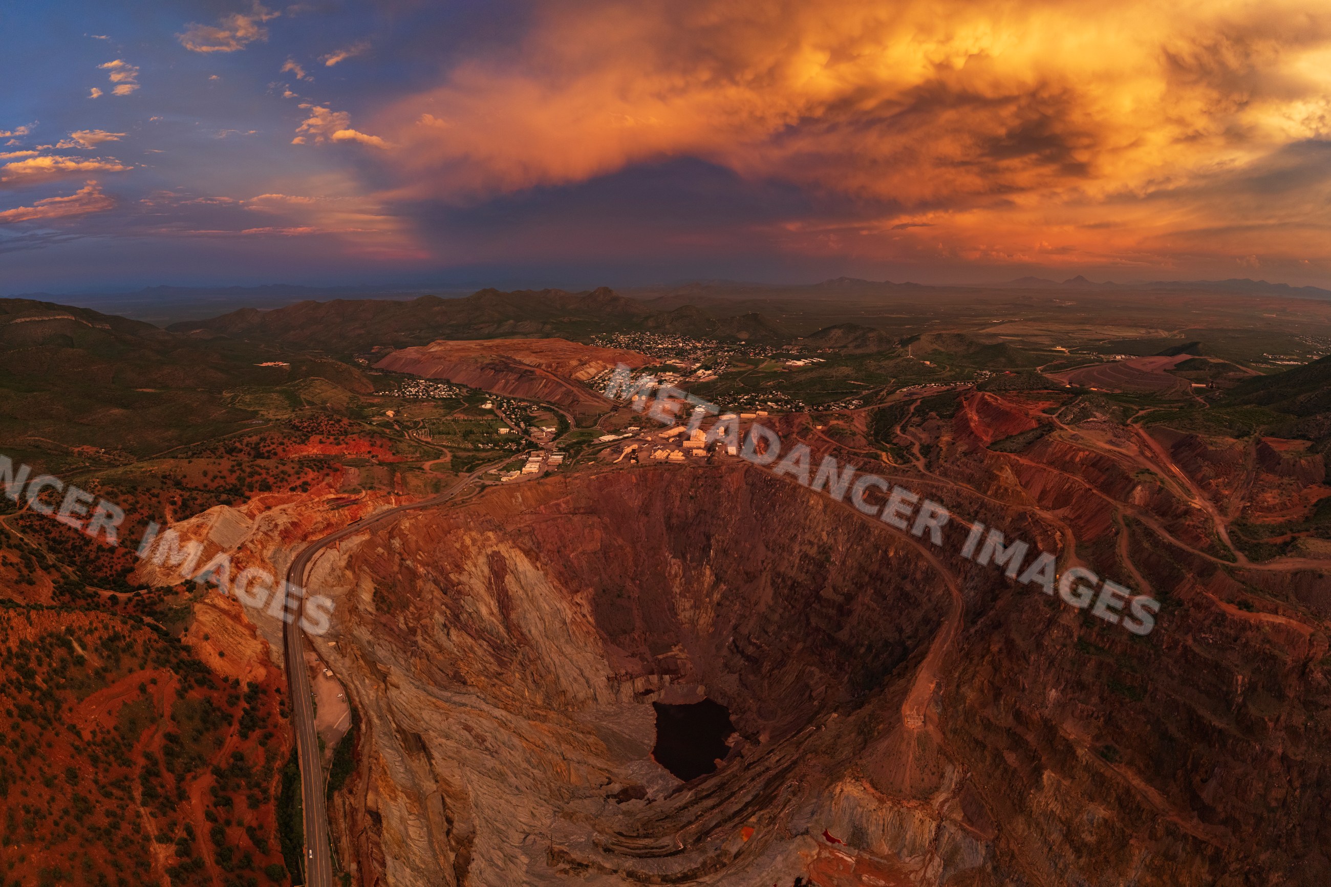Open pit mine with stormy sunset sky and surrounding landscape