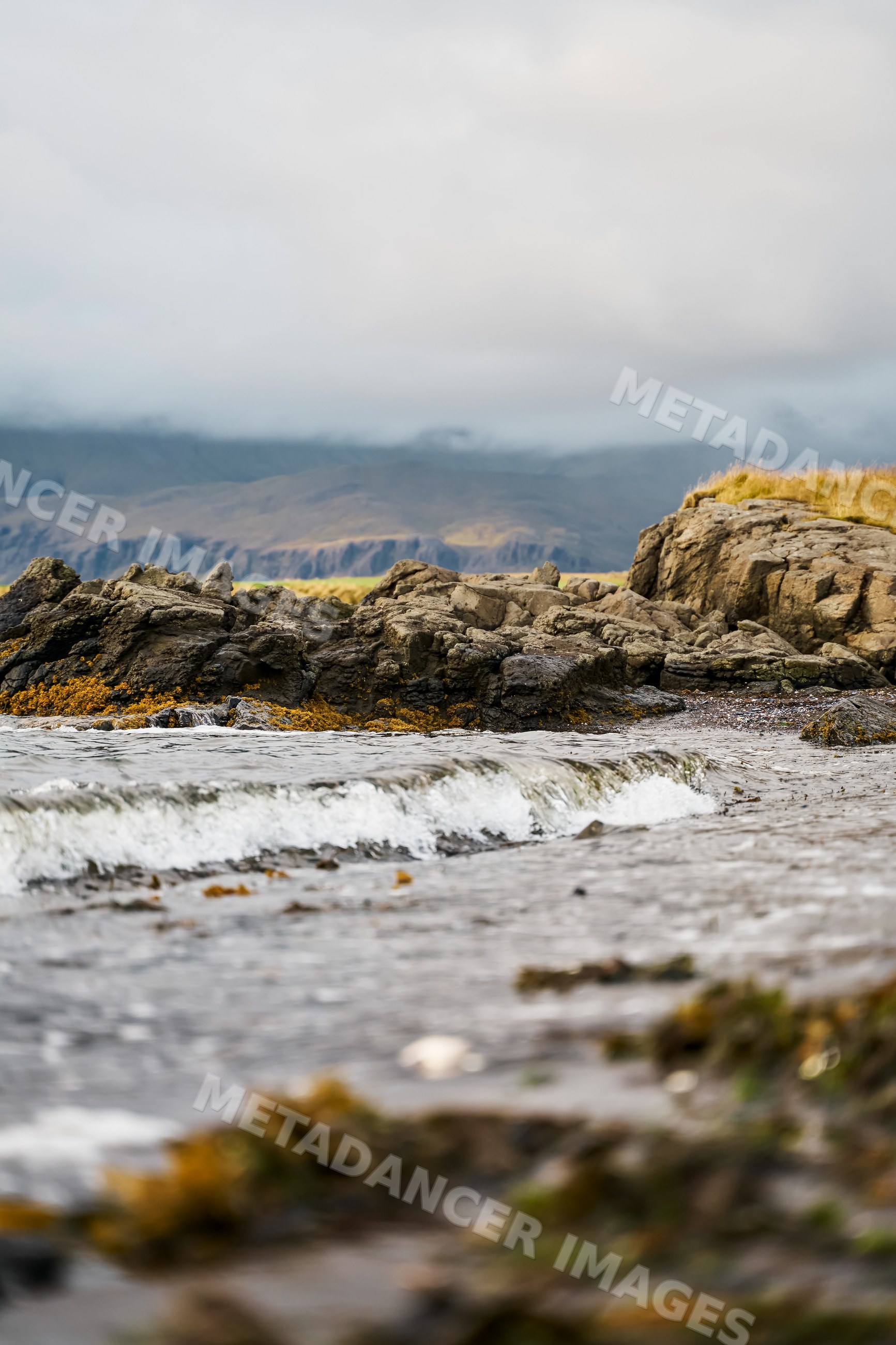 A small wave breaks on the rocky shoreline of Iceland's coast