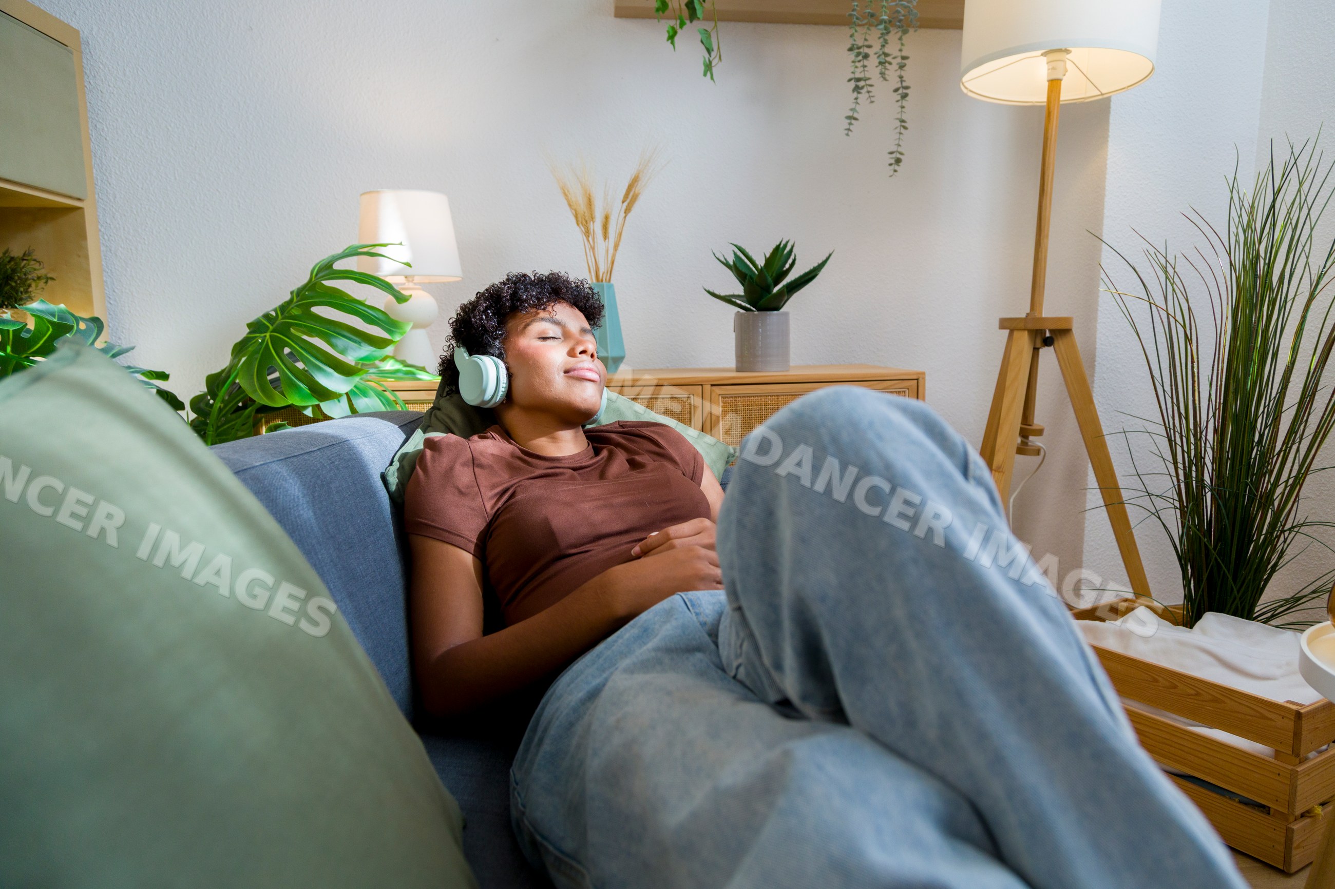 Young African American woman relaxing on sofa with headphones