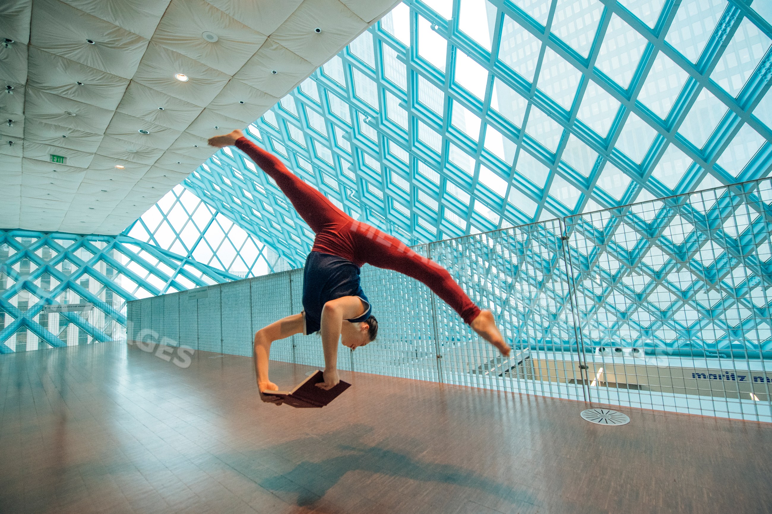 A woman doing a handstand split reading a book in a library