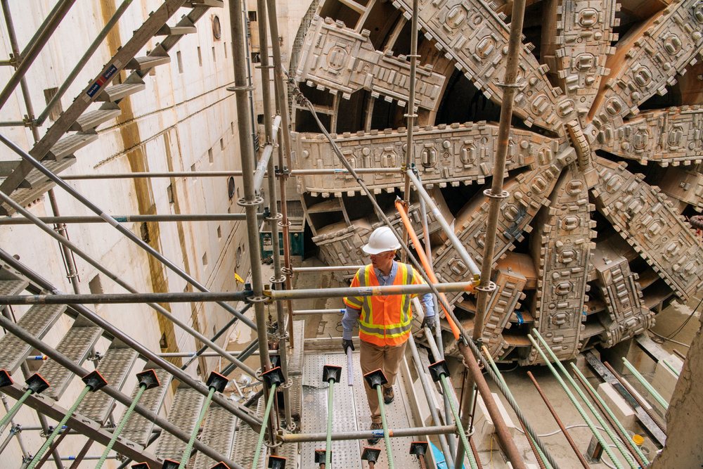 Two white construction workers inspecting a tunnel boring machine