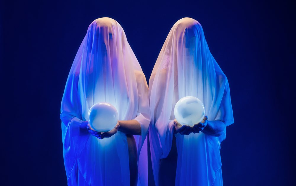 Ghostly figures holding glowing crystal balls in dark mystical scene