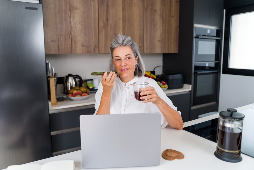 Middle aged white woman speaking on smartphone with coffee