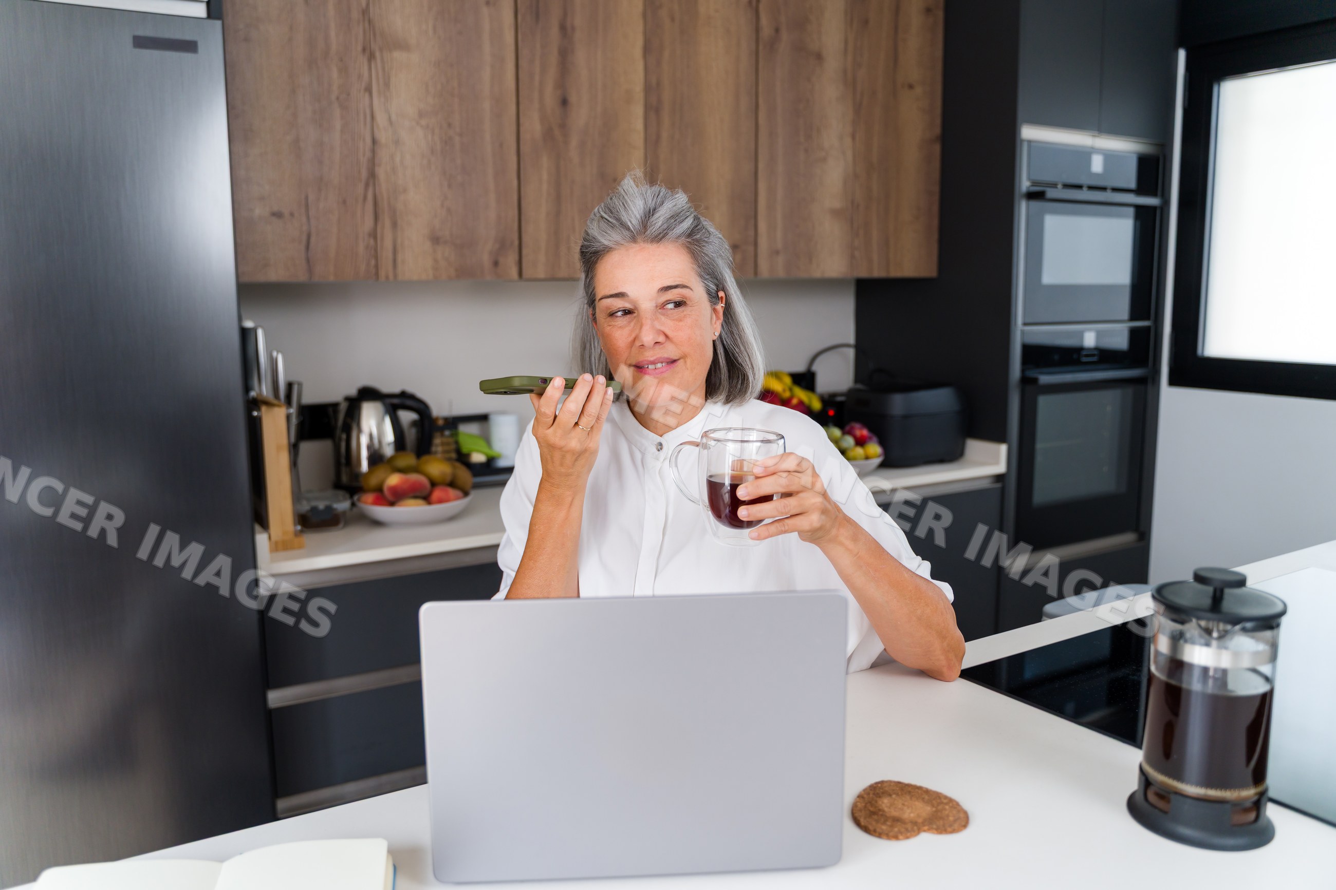 Middle aged white woman speaking on smartphone with coffee
