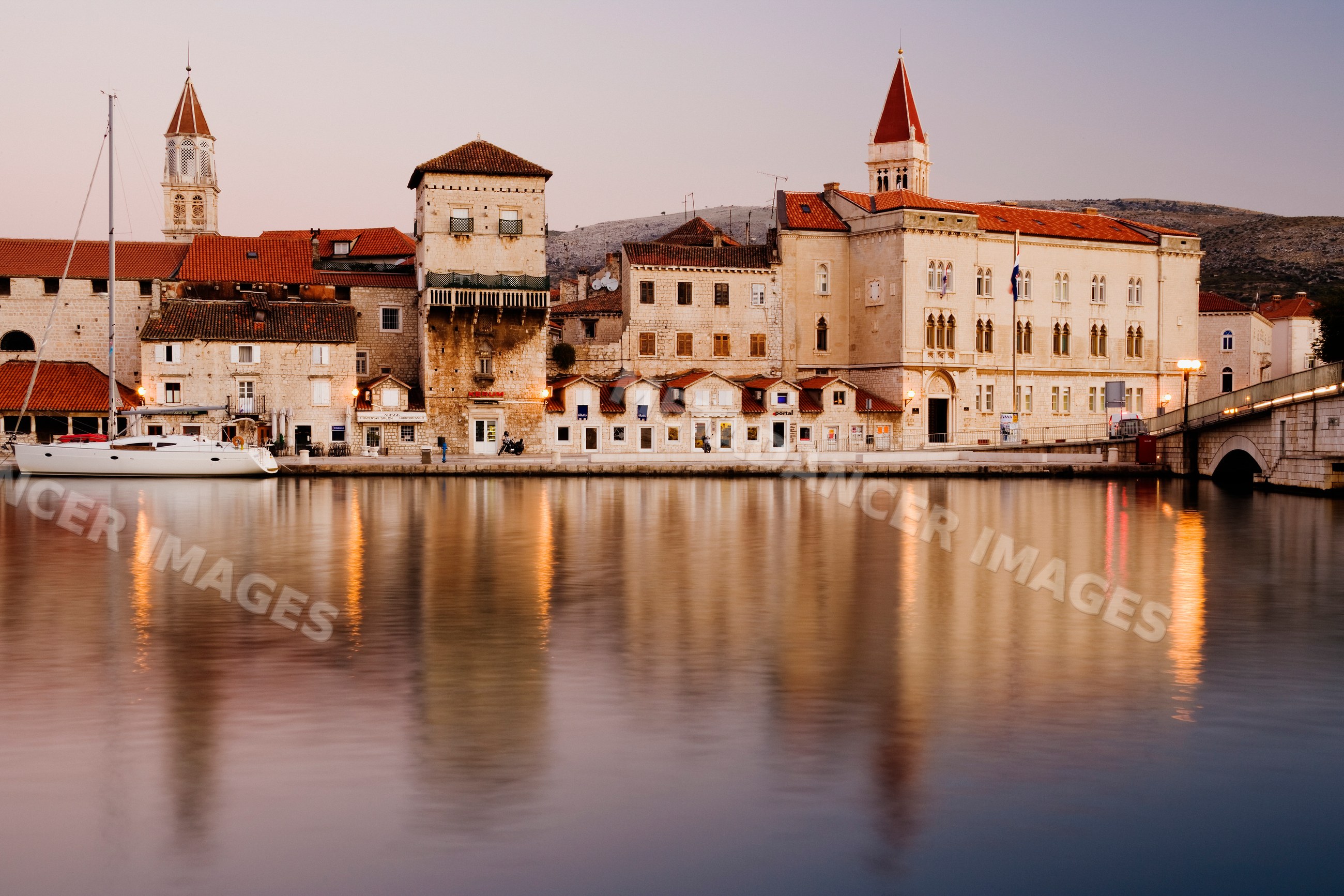 Town of trogir at dawn reflecting in harbor water