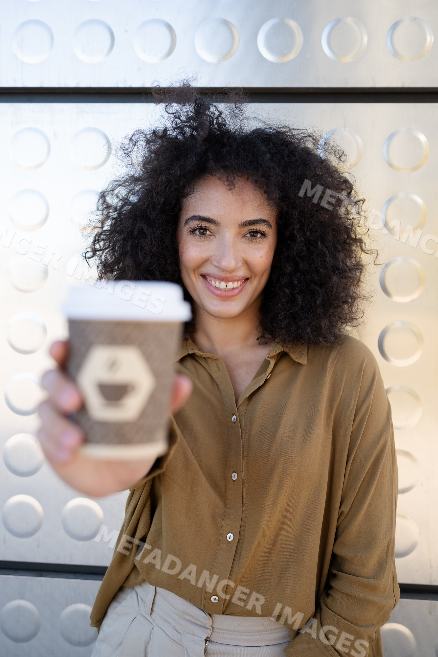 Woman holding takeaway coffee cup smiling outdoors