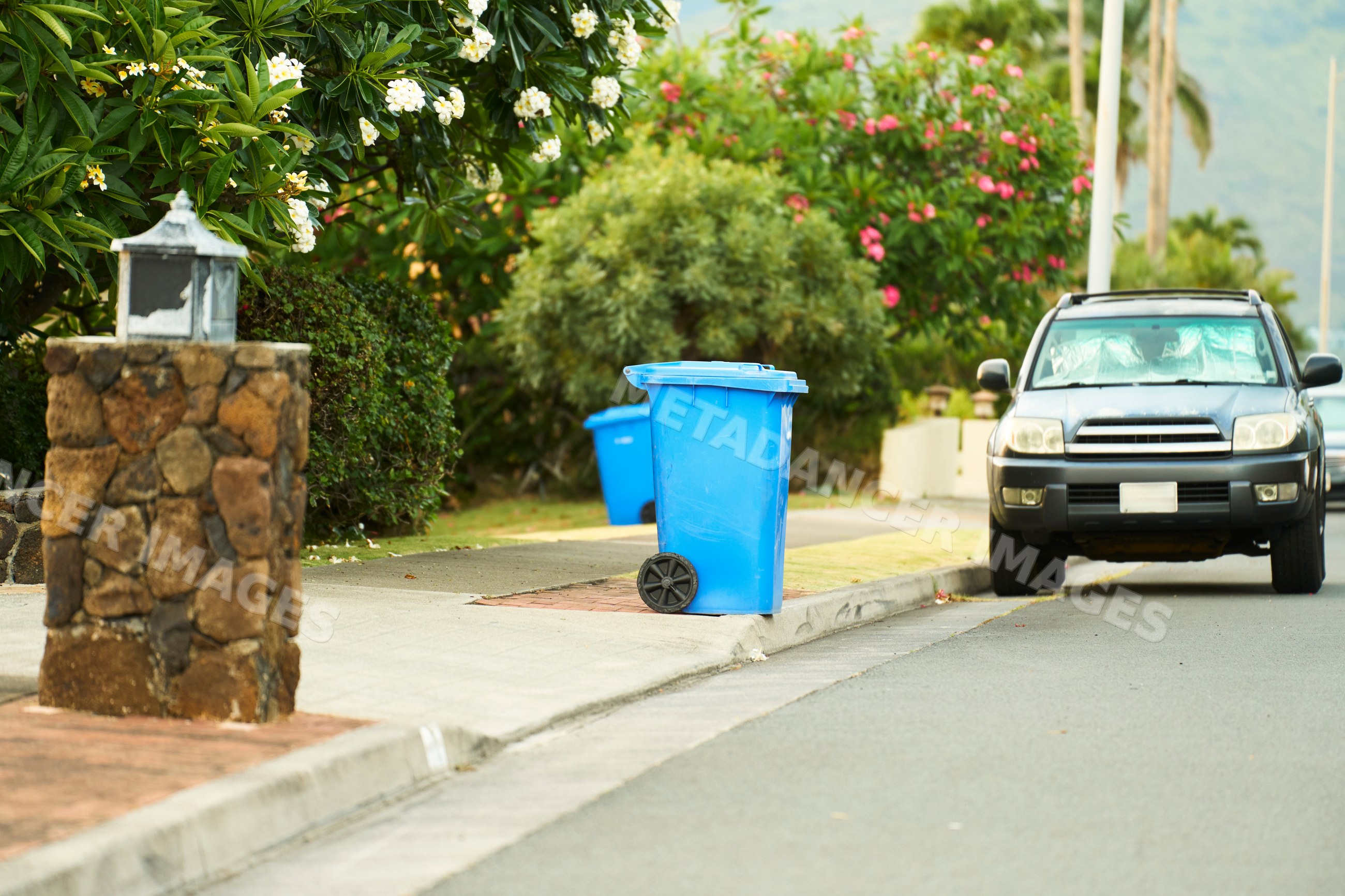 Blue trash bin on sidewalk