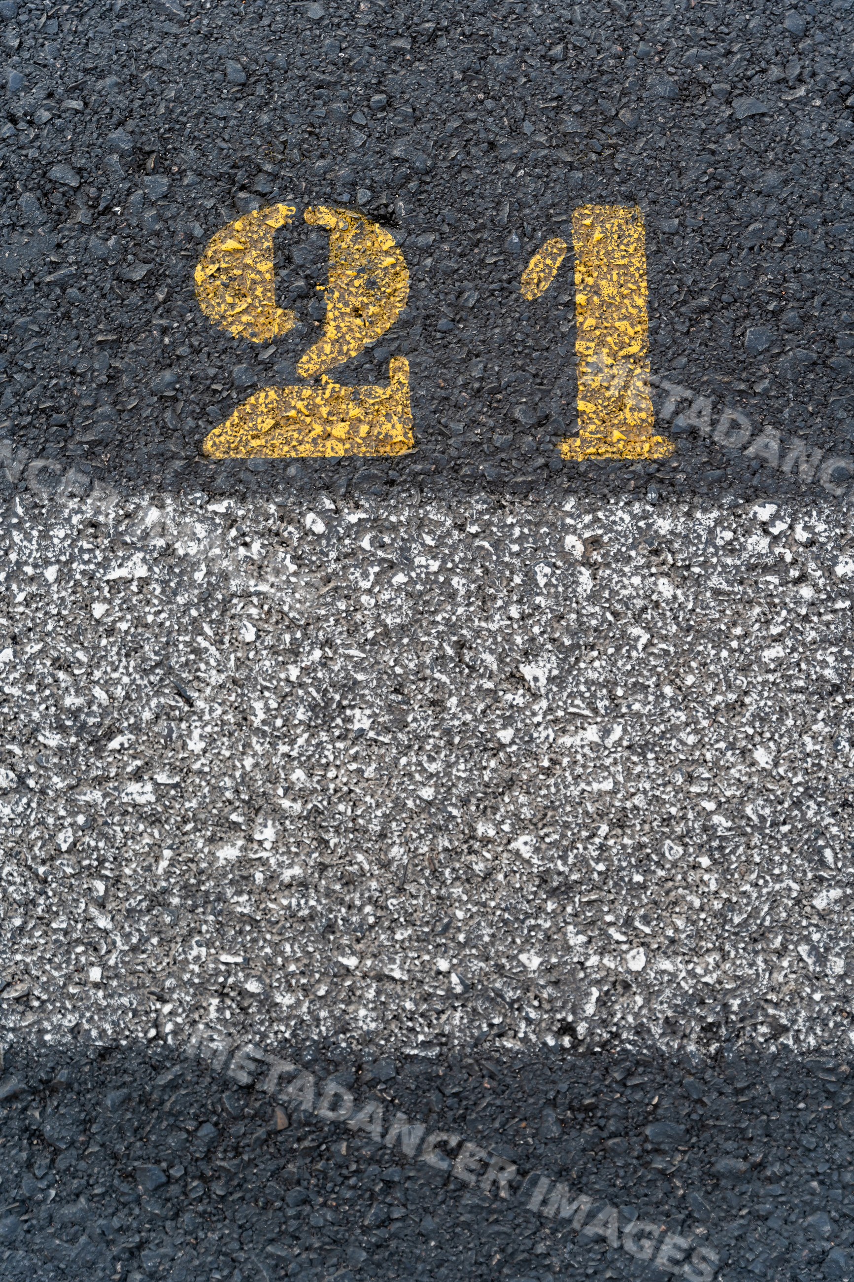 Road surface with yellow number 21 painted on asphalt