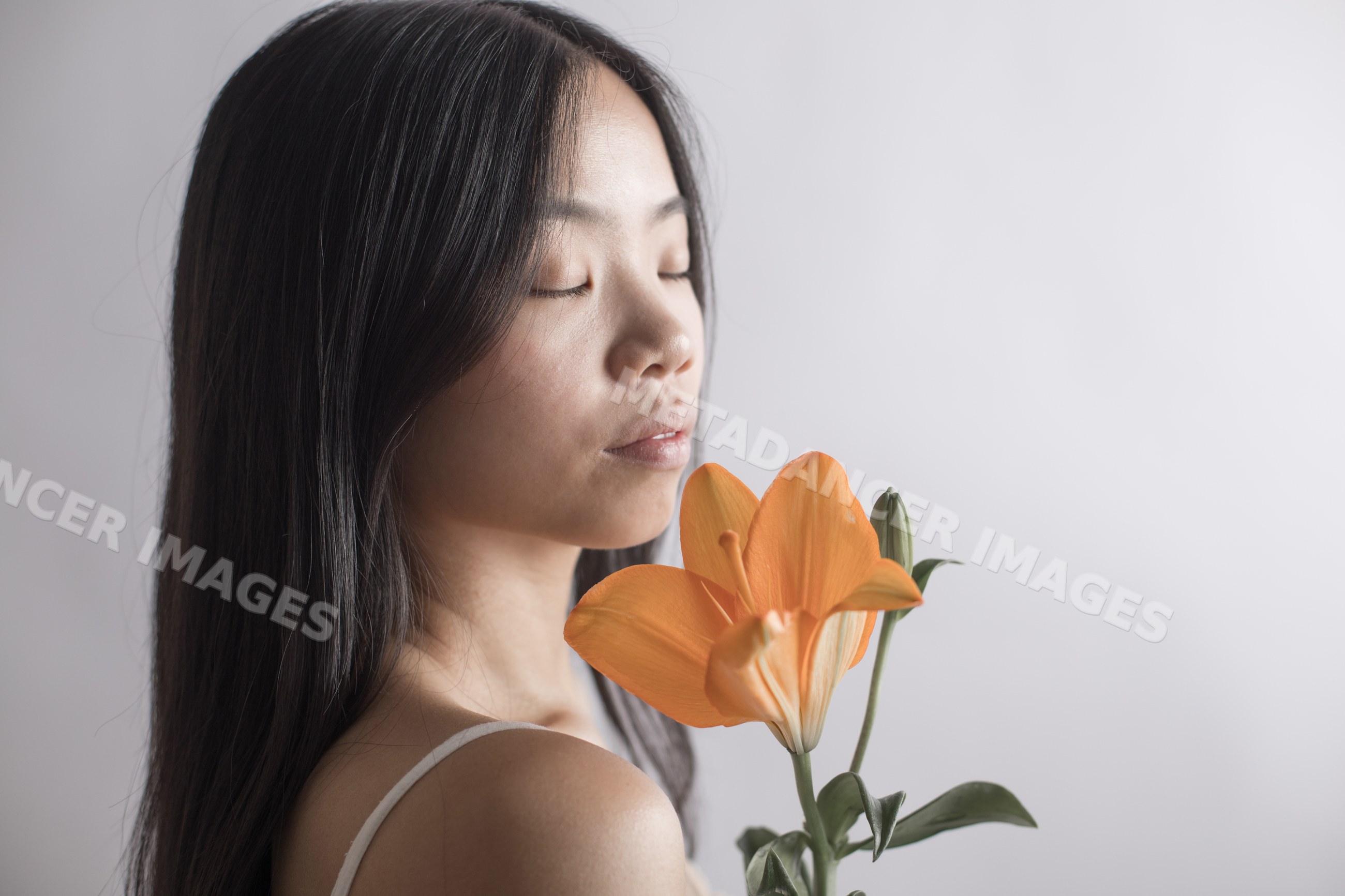 Southeast Asian woman holding an orange lily in a serene portrait