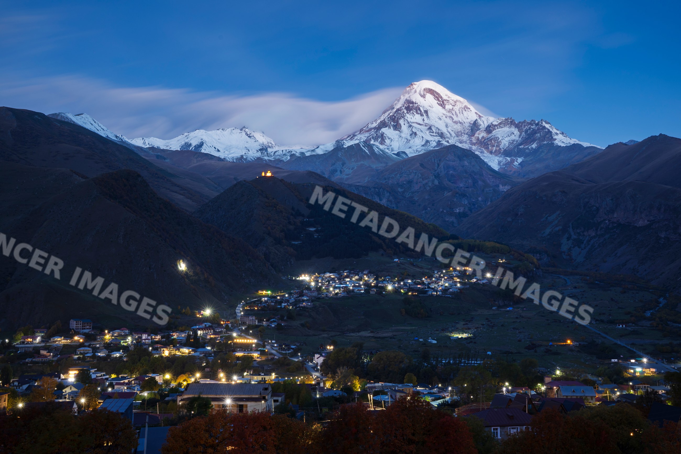 Mt kazbegi mountain at Dawn with village lights in stepantsminda