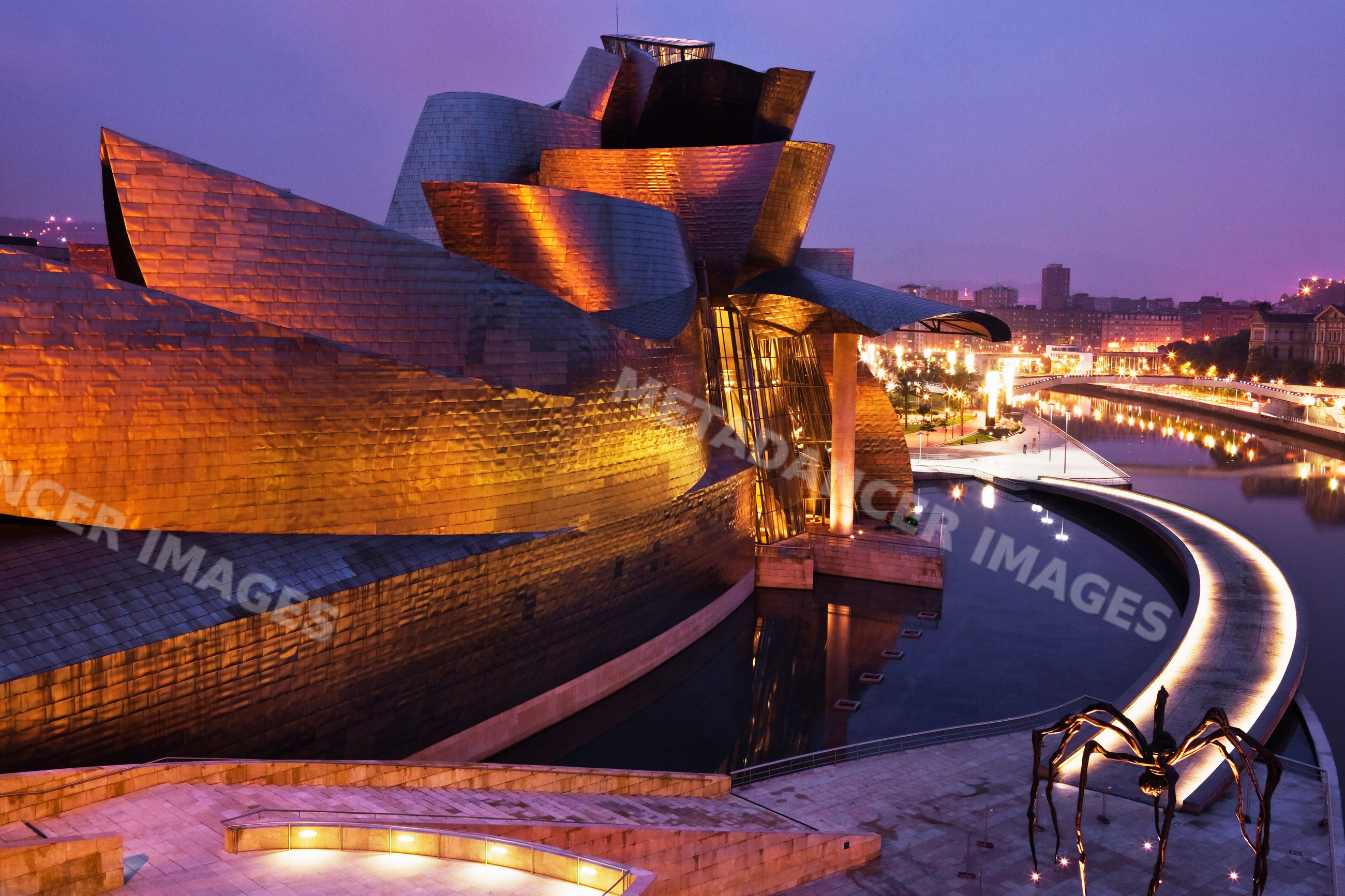 Guggenheim museum bilbao illuminated at dusk along the river