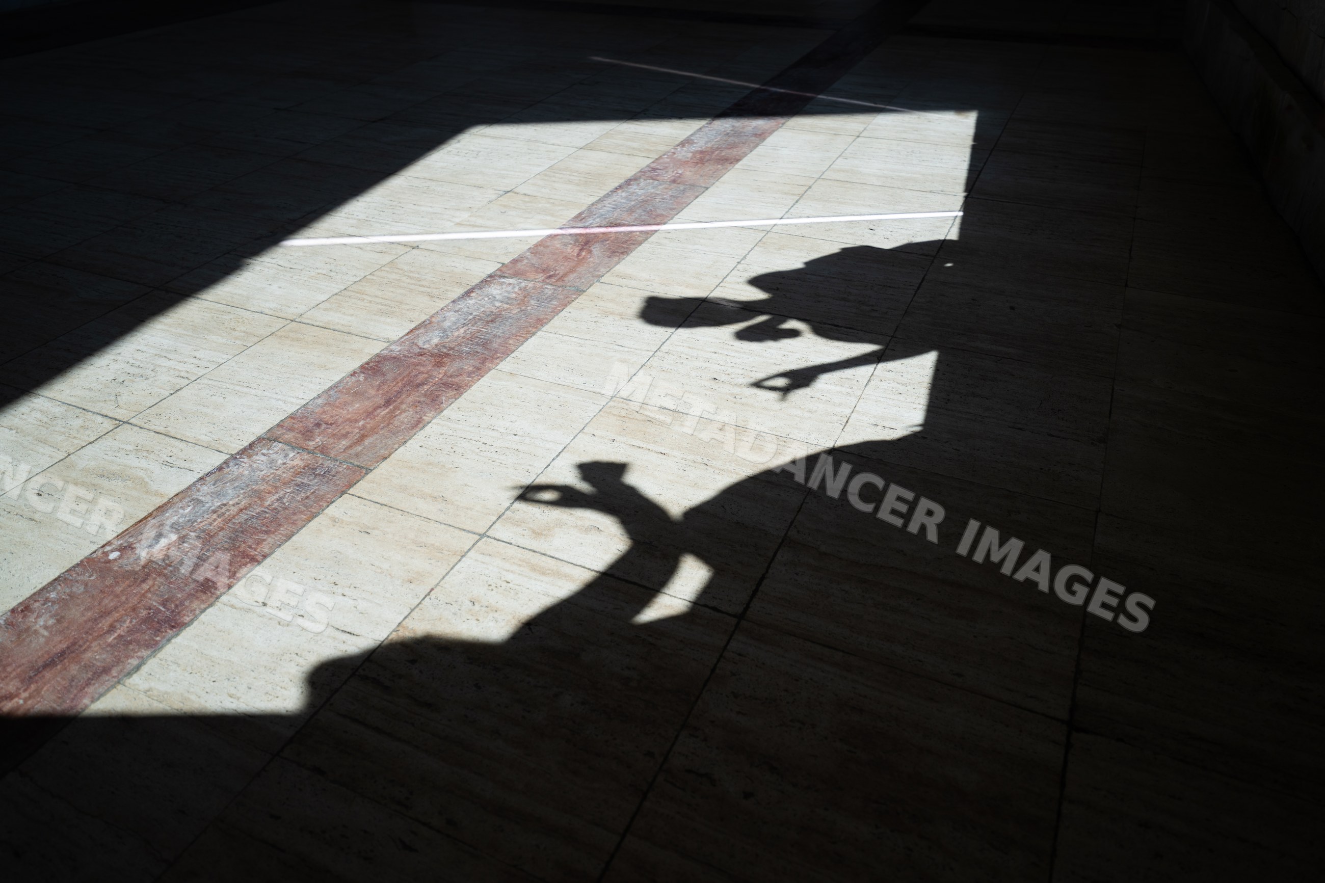 Shadows of two white people showing hand gestures on tiled floor