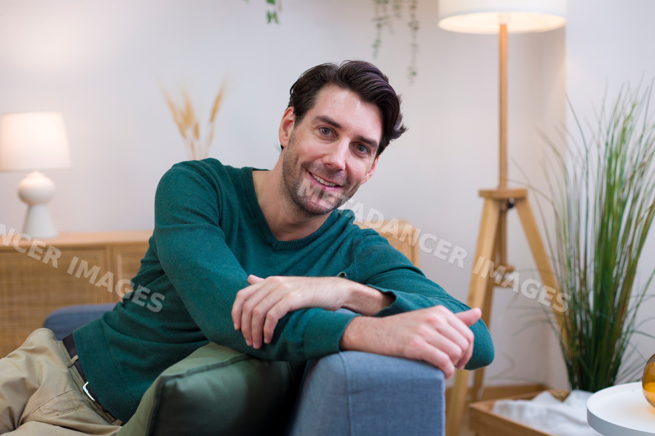 Smiling white man relaxing on sofa in modern living room