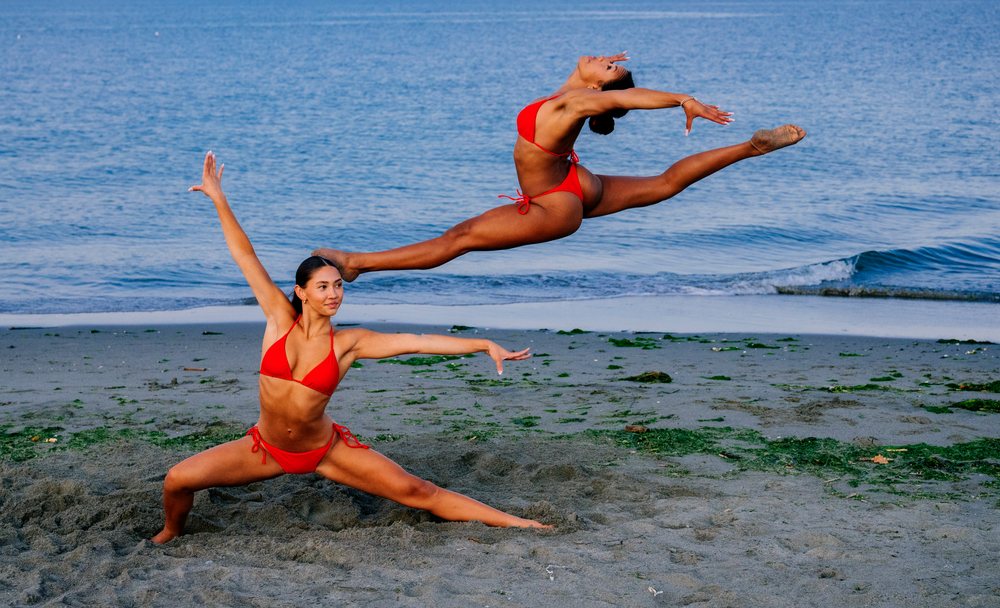 Two women perform partner acrobatics Yoga on a beach in WA, USA