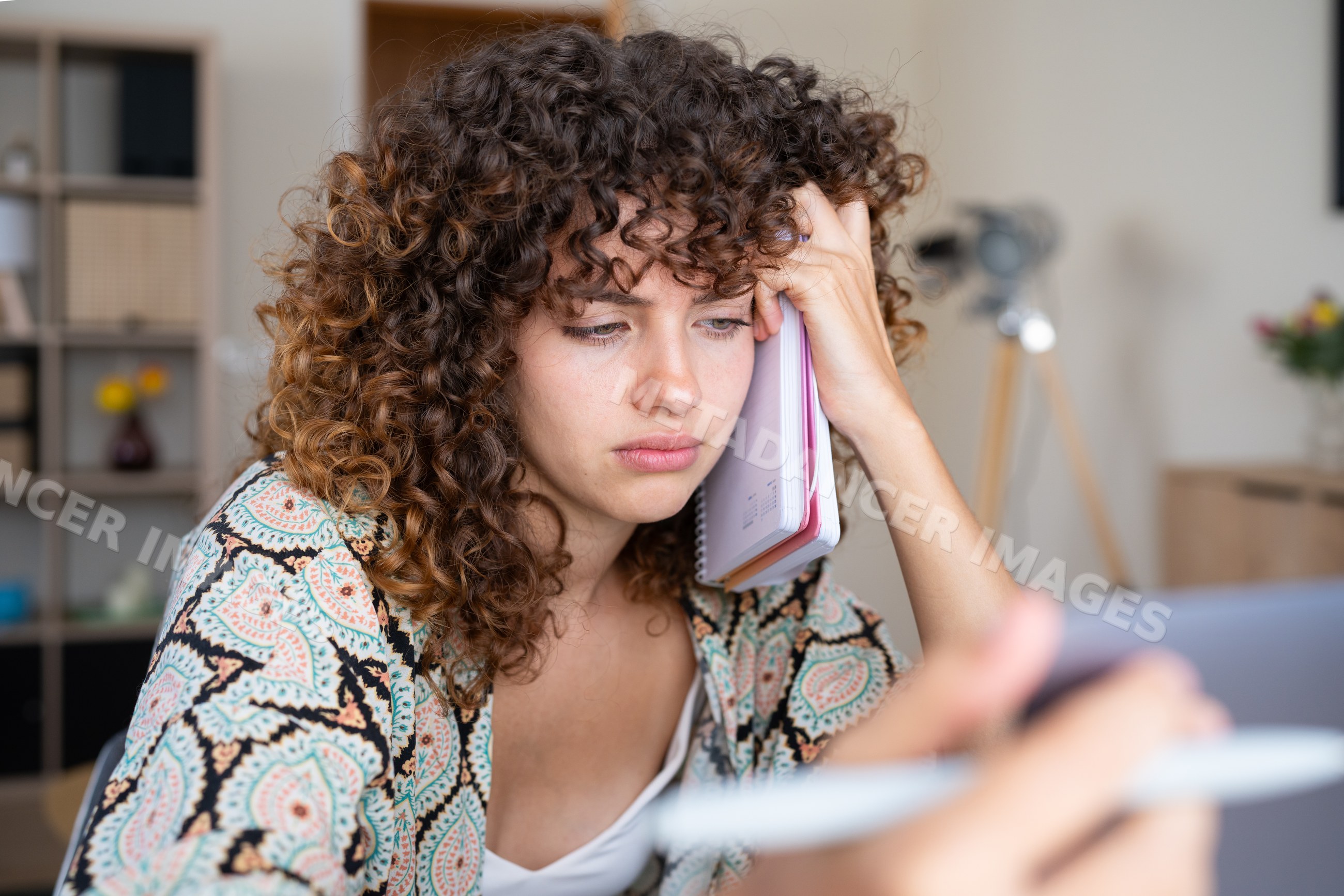 White girl holding notebook to ear while using tablet in a office