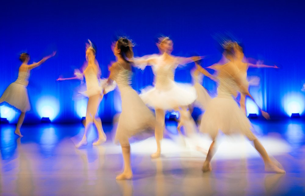 Ballet dancers perform holiday ballet on stage in white tutus