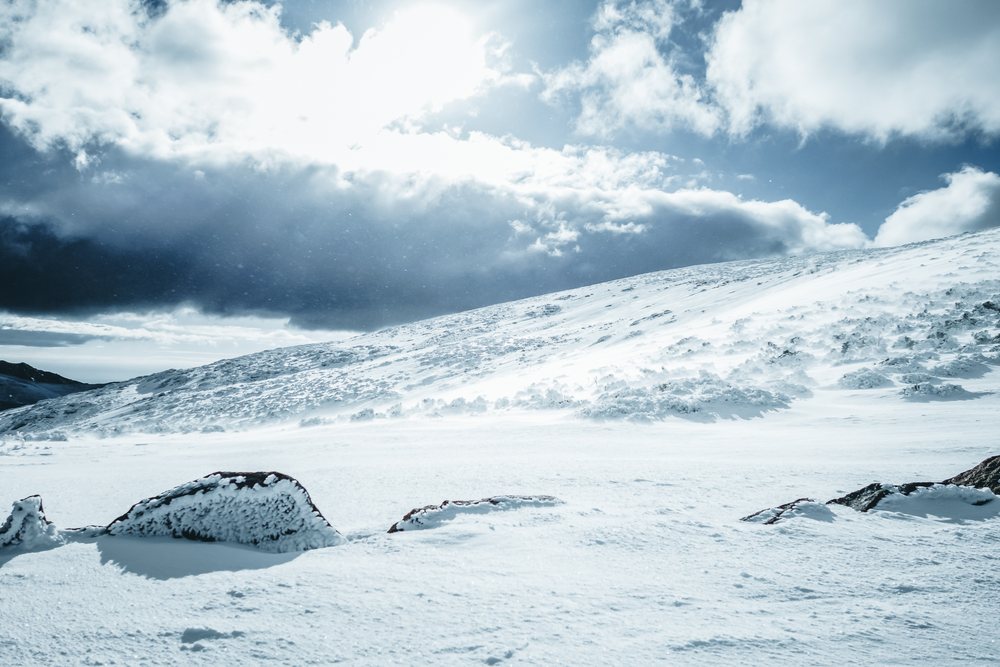 Snow-covered hill landscape with rocks and clouds