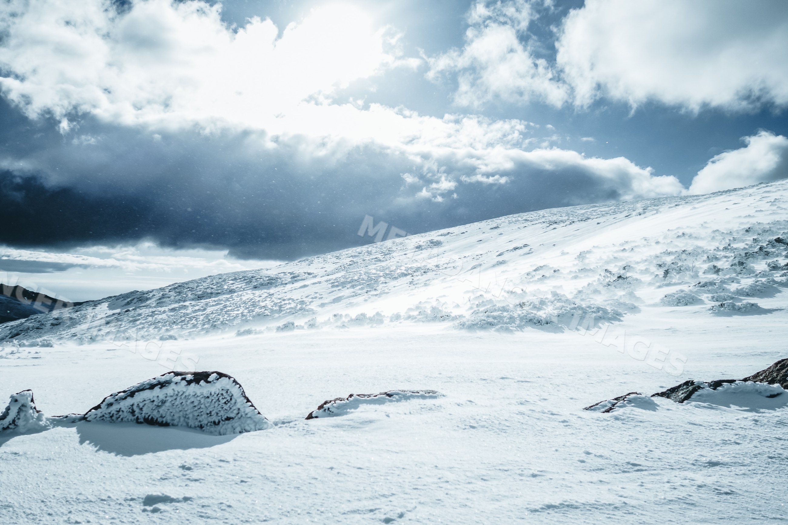 Snow-covered hill landscape with rocks and clouds