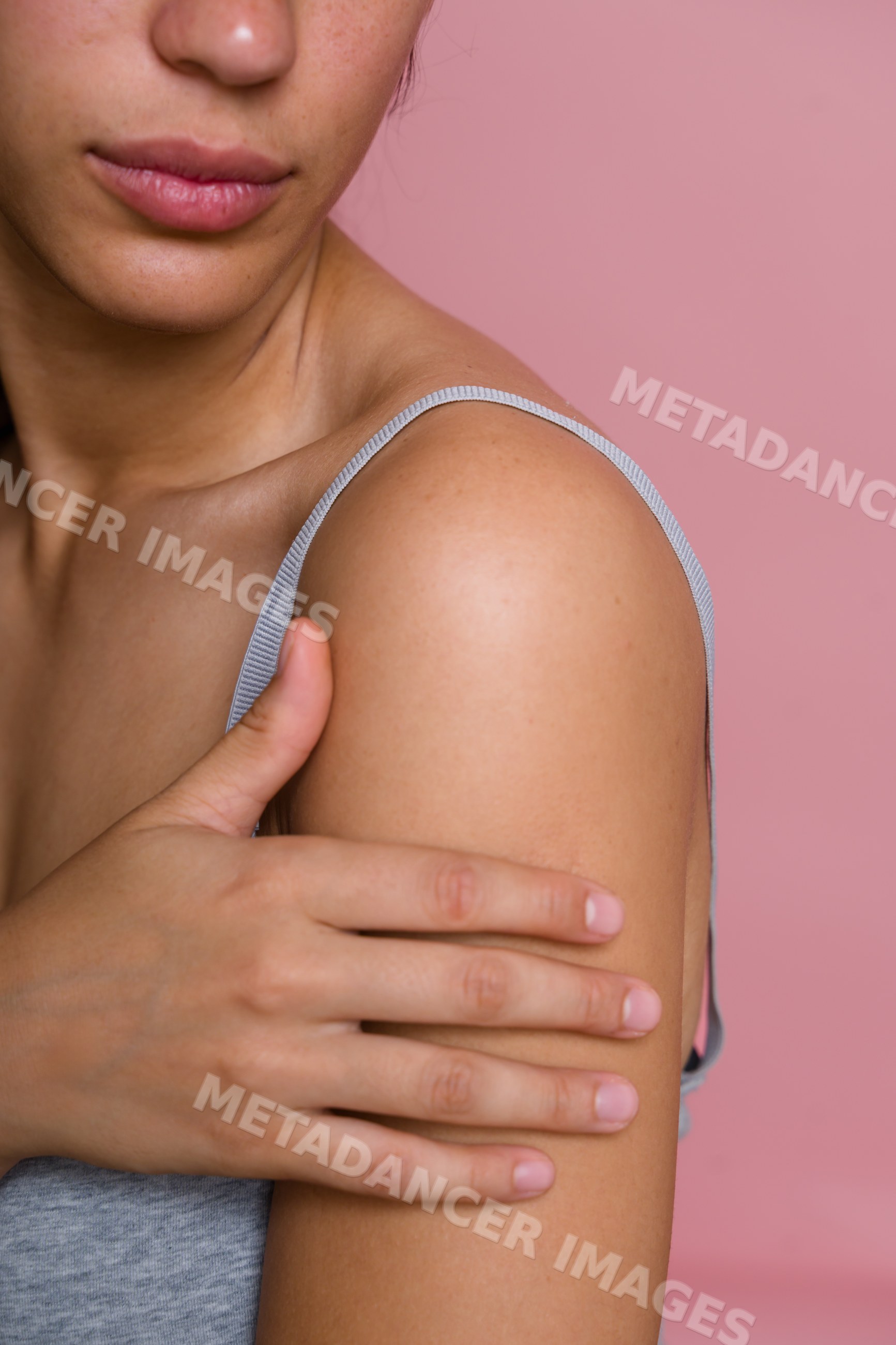 Hispanic woman touching shoulder showcasing smooth skin
