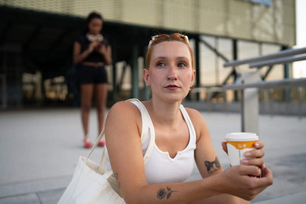 A young white woman sits outdoors holding a coffee cup in Santiago