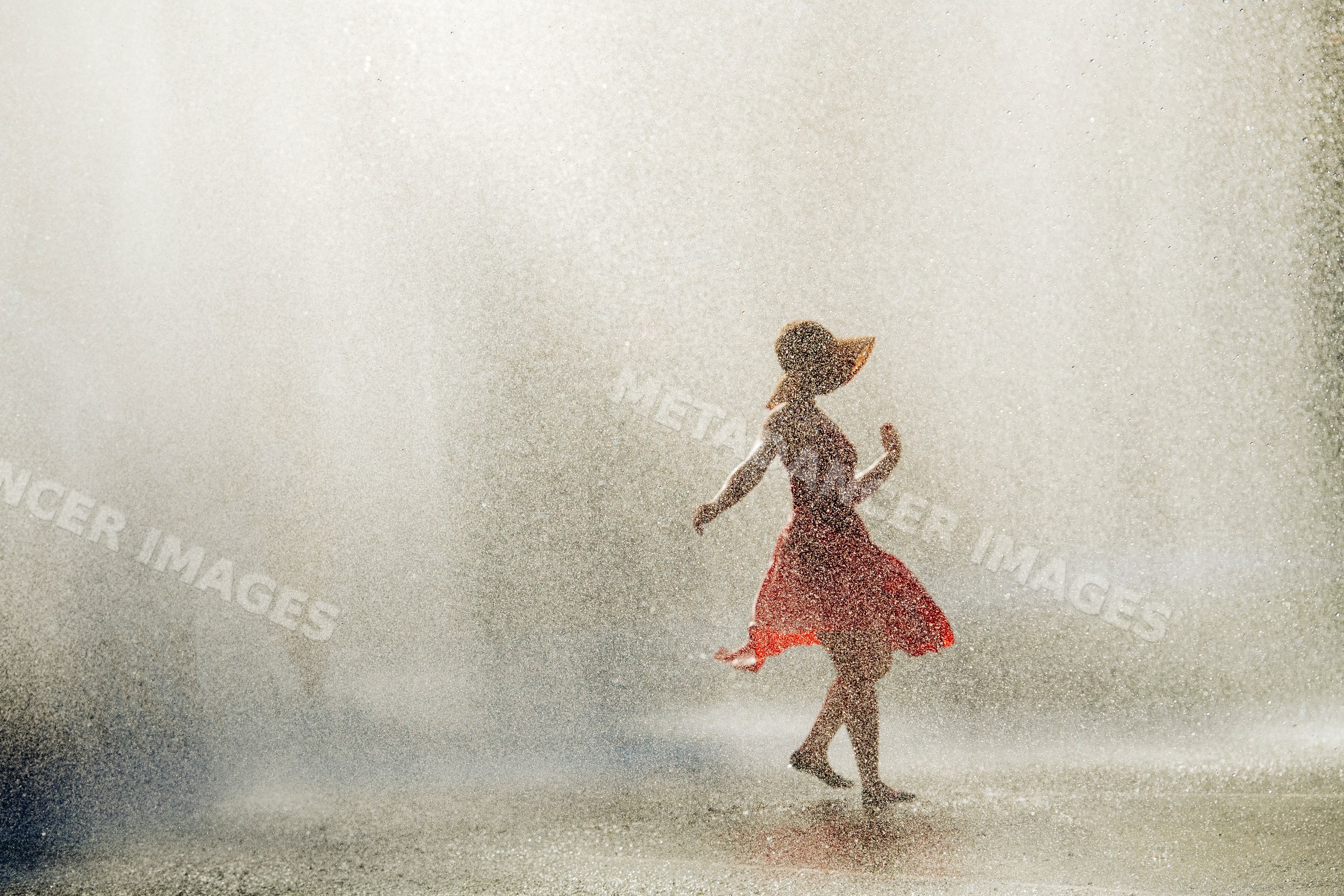White woman dancing joyfully in water spray outdoors in summer