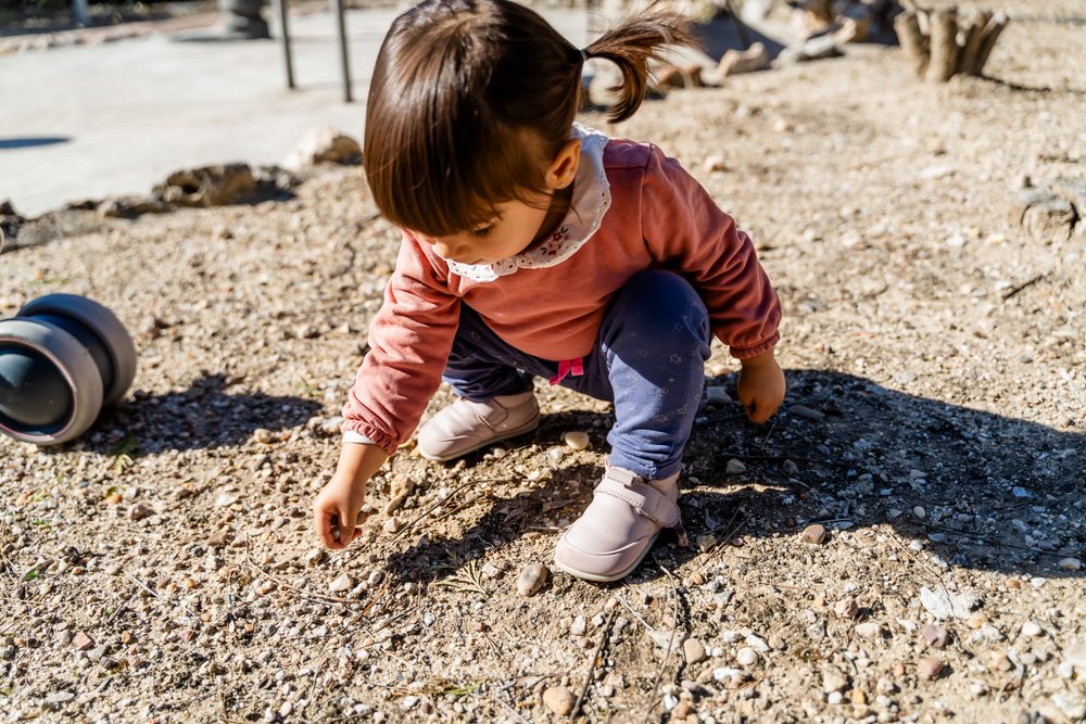 Toddler playing and picking rocks outdoors
