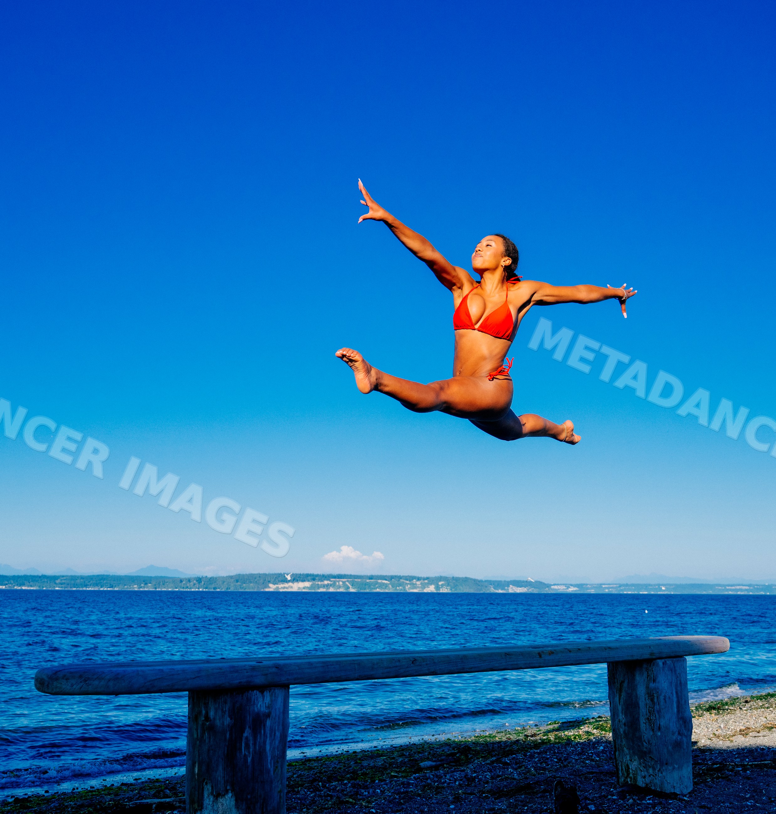 Woman jumping in split leap pose on beach in washington USA