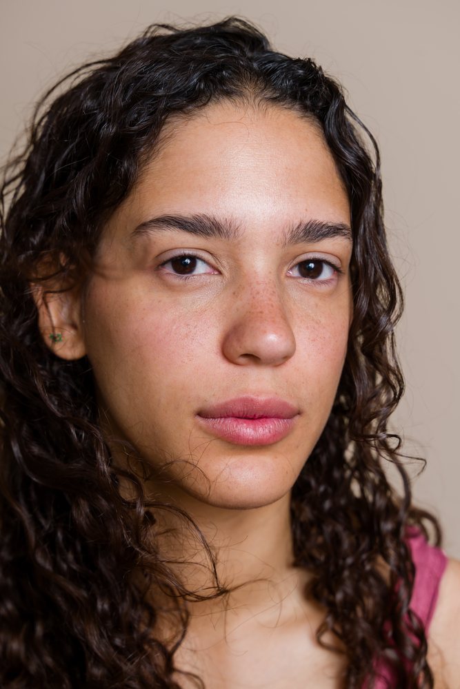 Close-up portrait of a Hispanic woman with curly hair and freckles