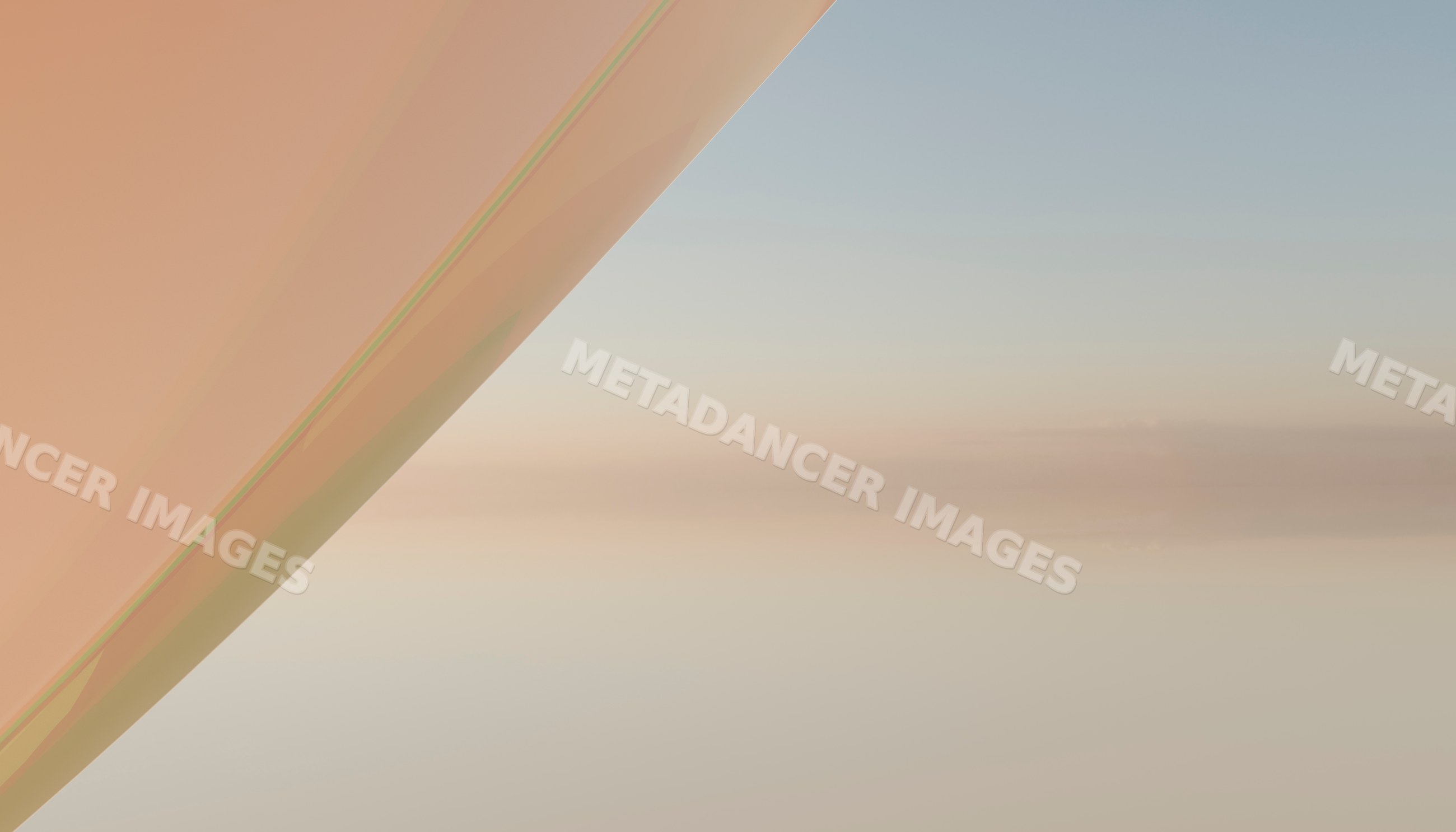 View of an airplane wing with clear sky and soft clouds during daytime