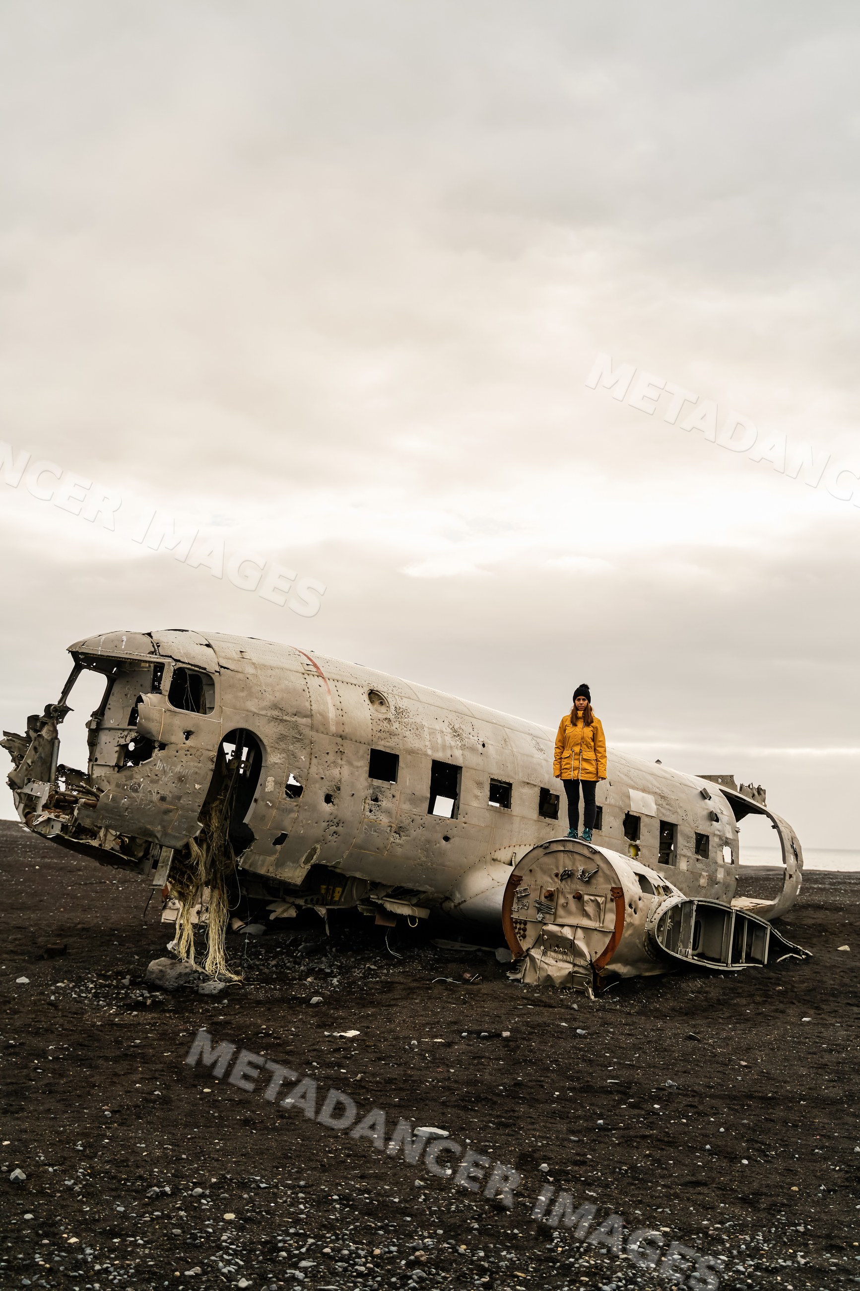 A white woman stands on an abandoned crashed airplane fuselage