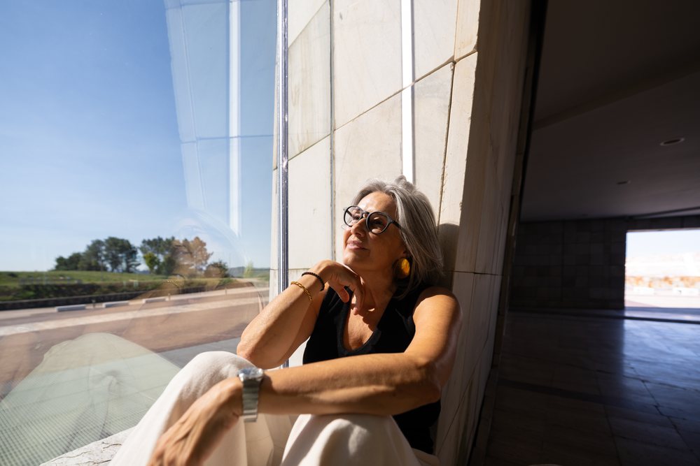 White woman sitting by window inside modern building in Spain