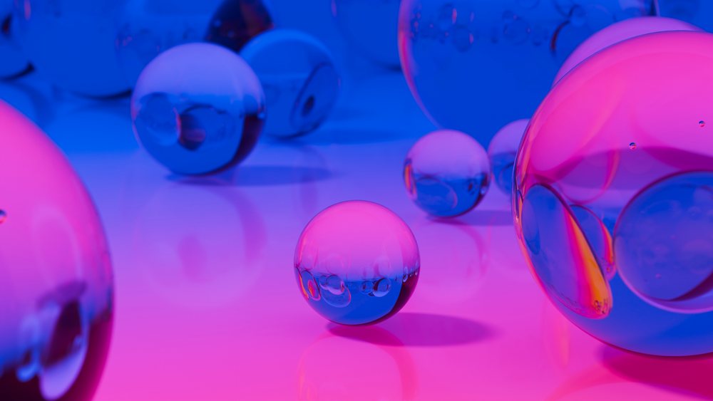 Transparent glass spheres reflecting blue and pink light on a smooth