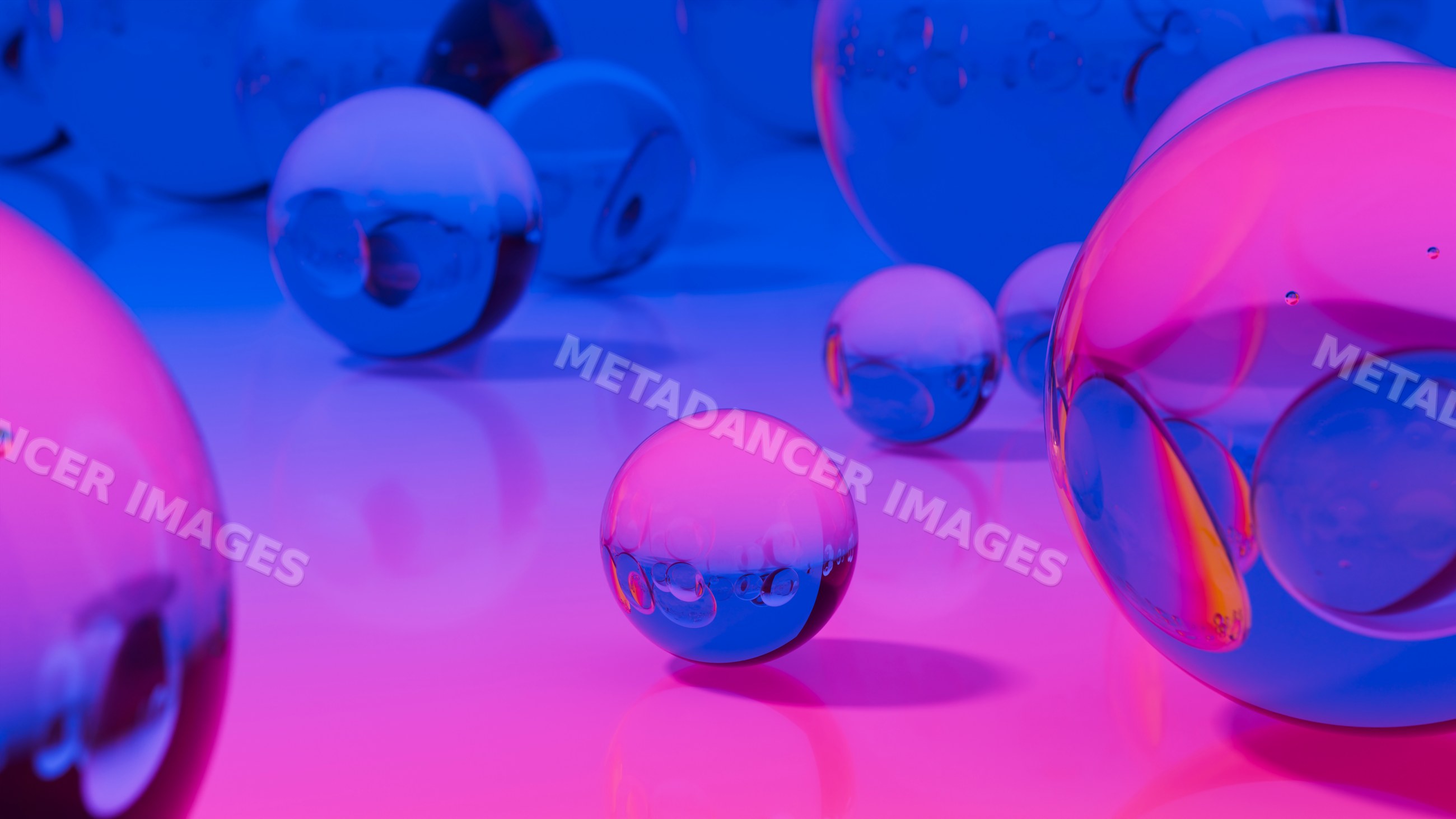 Transparent glass spheres reflecting blue and pink light on a smooth